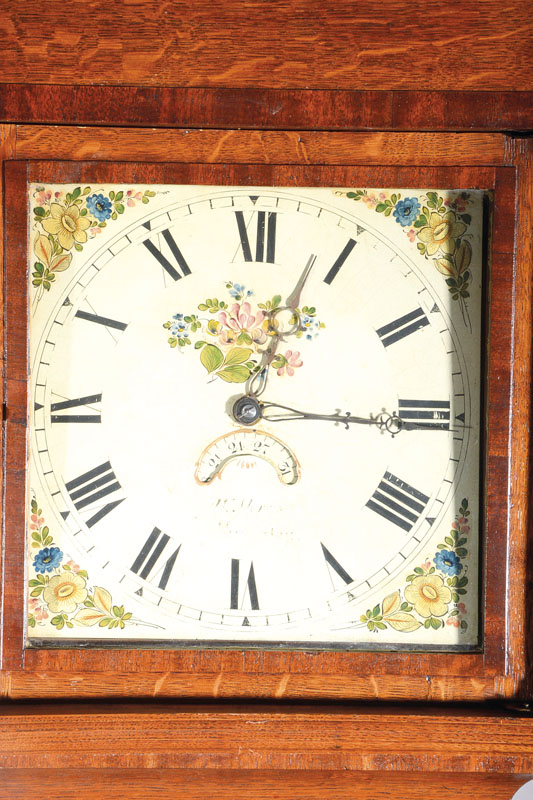 Detail a: Standuhr, England um 1820/30, Gehäuse im Stil der Zeit, Eiche mit Nußbaum, profiliert, Sockel mit Spannungsriß, in Türfüllung intarsierte ...