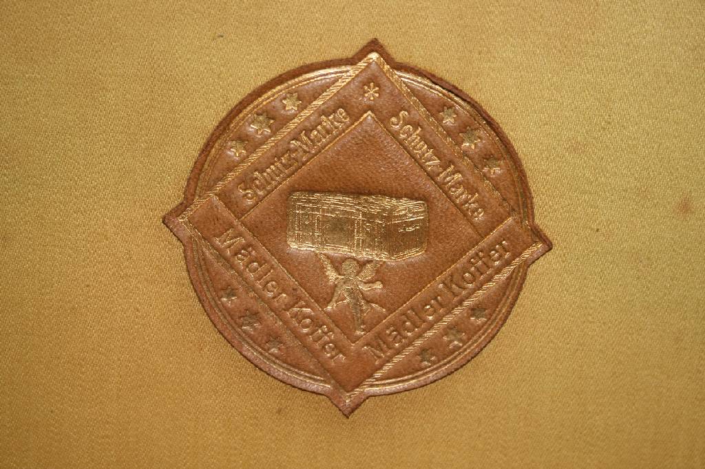 Detail d: Mädler Kofferfabrik Leipzig, um 1925, wasserfester Leinenbezug mit Lederkante, Innen original Ledermarke, Außen zwei original farbige Blechschilder ...