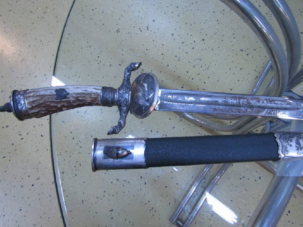 Detail g: Hirschfänger, deutsch/Solingen, 50er Jahre, Bakelitgriff mit erhabenem Eicheldekor, z.T. mit Bronzeverzierungen, Scheide mit Hirschdarstellung, ...