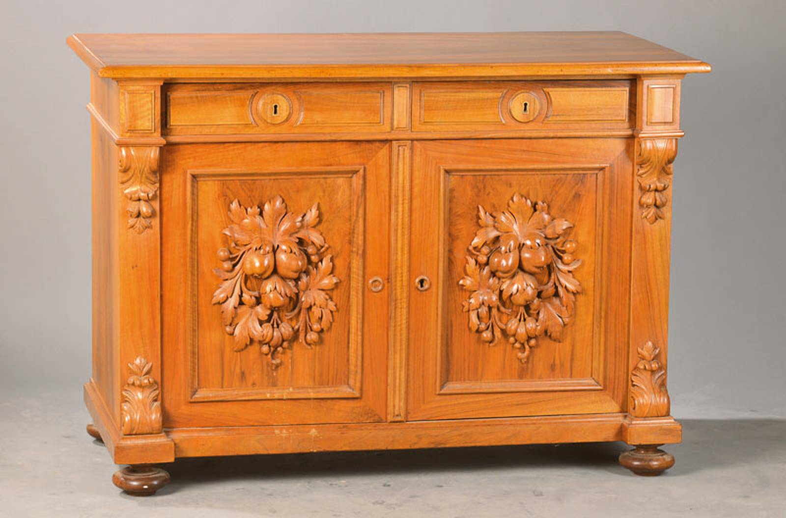 Halbschrank, deutsch, um 1900/10, Nussbaum massiv u. hell, 2-türig, 2-schübig, plastisch gearbeitetes Frucht- u. Blattwerk in den Kassetten, wohl ...