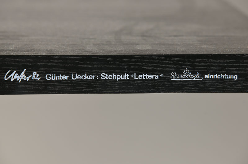 Detail a: Stehpult "Lettera" Entwurf Günther Uecker, 1982, Eiche schwarz lackiert, Tischkante mit Spruch des Künstlers: "Gehend einen Gedanken ...