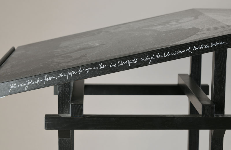 Detail b: Stehpult "Lettera" Entwurf Günther Uecker, 1982, Eiche schwarz lackiert, Tischkante mit Spruch des Künstlers: "Gehend einen Gedanken ...