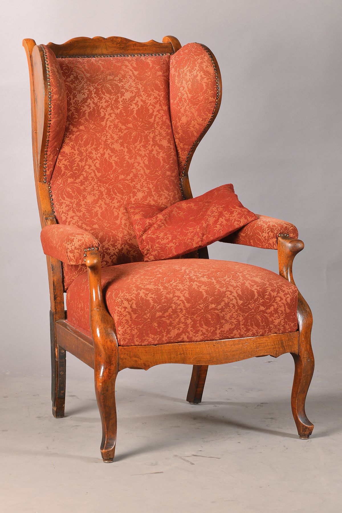 Ohrenbackensessel, südwestdeutsch, wohl Mainz, um 1820/30, Nussbaum massiv u. furniert, allseitig geschweifte Form, in sich gewölbte Rückenlehne, ...