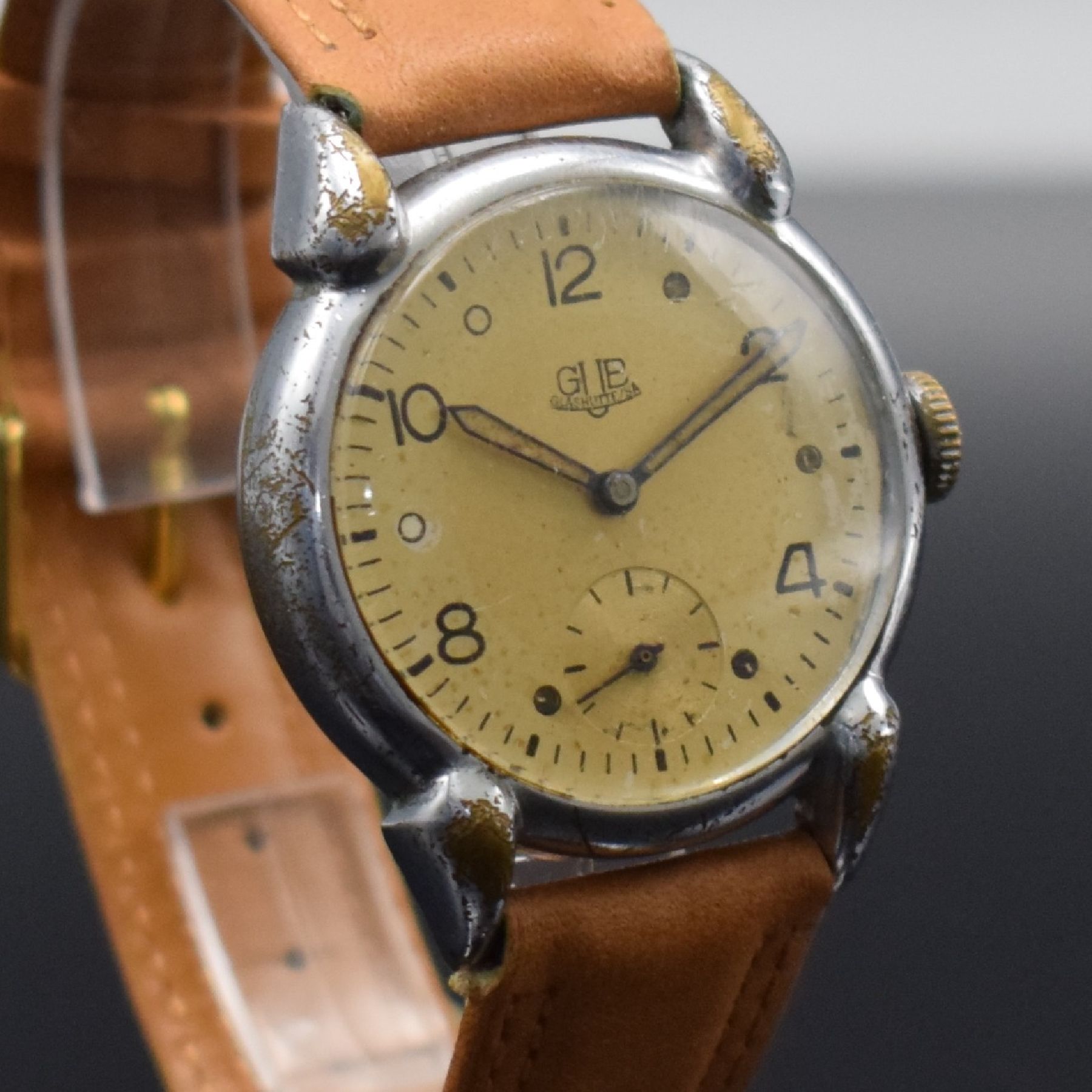 Detail e: GUB Herrenarmbanduhr mit Kaliber 60, Handaufzug, DDR um 1952, verchr. Metallgeh. m. ausgef. Bandanst. ber., Edelstahlboden aufgedr., silb. Zifferbl. ...