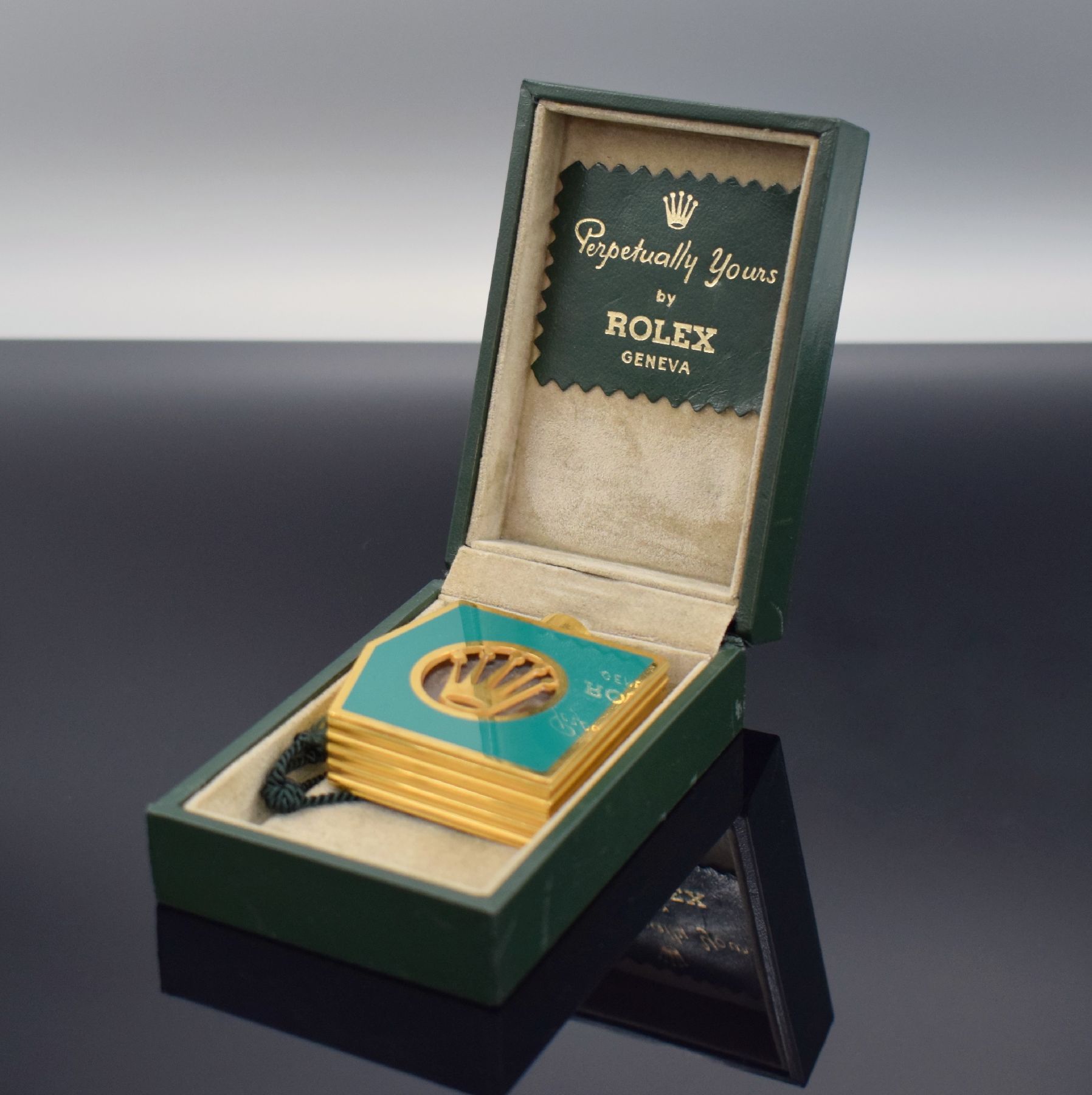 ROLEX seltenes Parfum-Flakon, um 1970, vergoldet & grün lackiert, seitl. Rillendekor, Innen m. Glaskorpus, M. ca. 58 x 53 x 16 mm, orig. Etui anbei, ...
