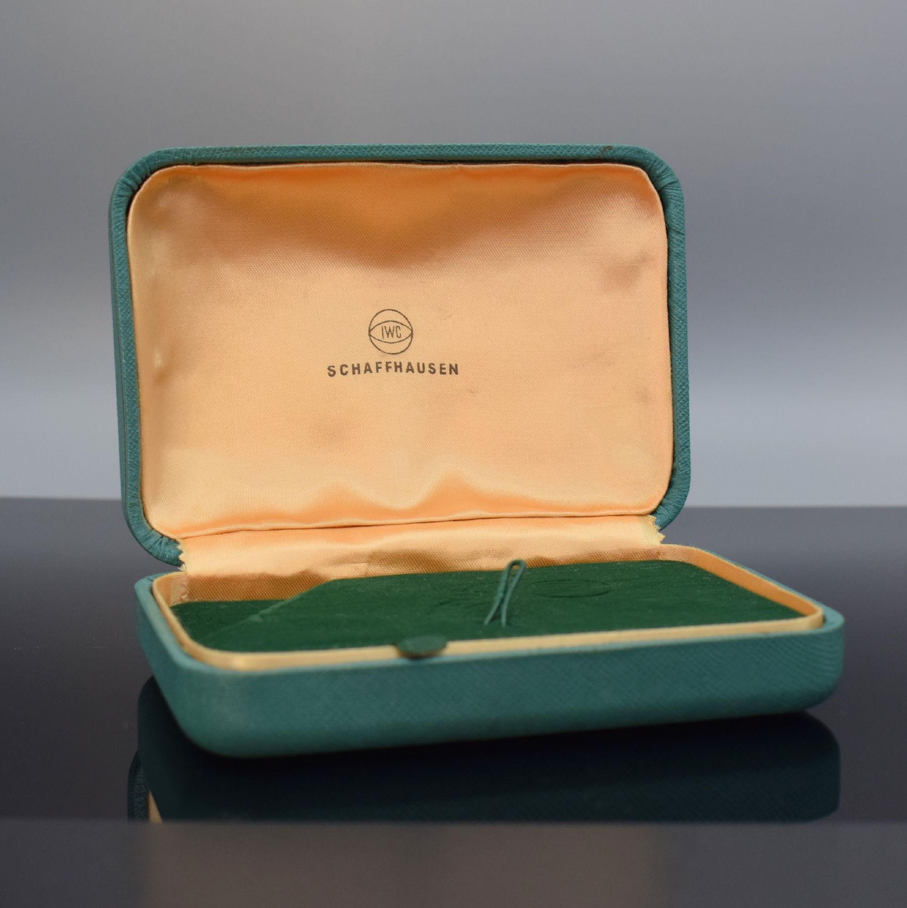 IWC seltene Armbanduhr-Box, Schweiz um 1960, Aussen m. Stoff bezogen, gefederter Deckel, innen grüner Samt bzw. goldfarb. Stoff mit IWC Symbolik, ...