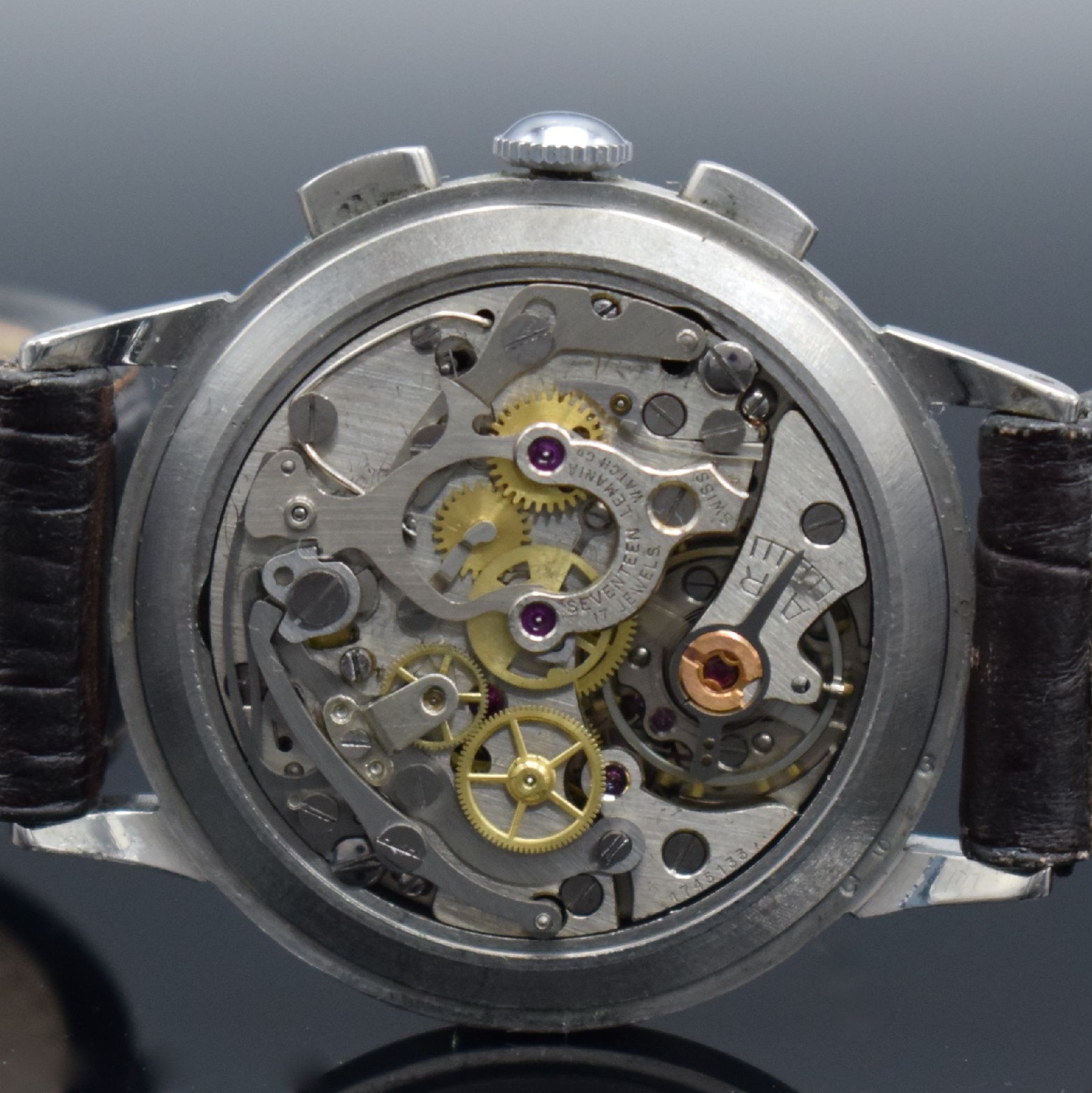 Detail e: LEMANIA Armbandchronograph in Stahl, Handaufzug, Schweiz um 1960, 3-teil. Edelstahlgeh., Boden & Glasrand aufgedr., silb. Zifferbl. m. gold. aufges. ...