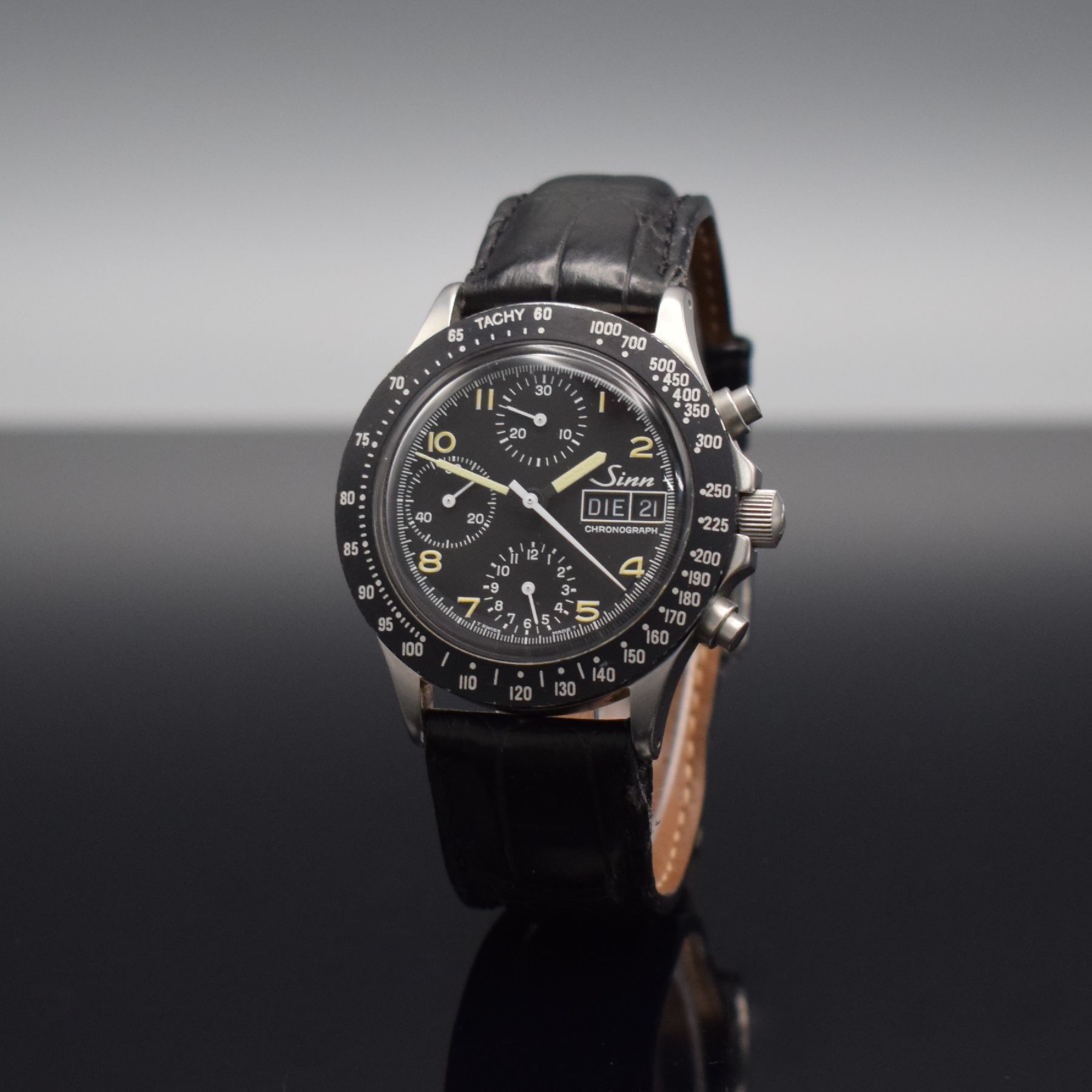 Detail b: SINN Herrenarmbanduhr mit Chronograph, Schweiz um 1990, Automatik, verschr. Edelstahlgeh., Tachymeterskala, schwarzes Tritium-Zifferbl. m. arab. ...