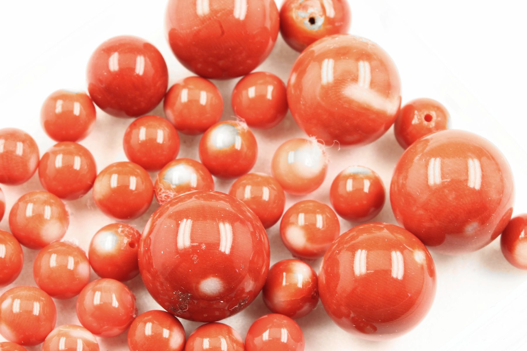 Detail c: Konvolut Korallenkugeln, zus. ca. 204 ct, versch. Größen und Farbnuancen, nat. Maserung, z.T. gebohrt, Versand nur innerhalb der EU