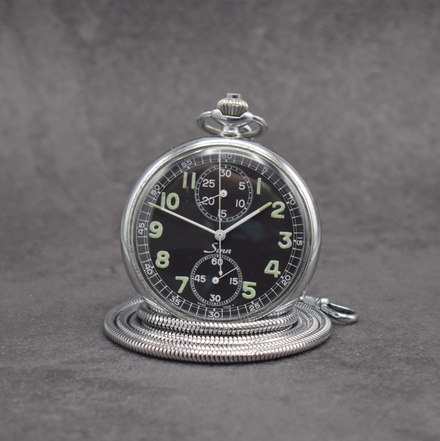 SINN Taschenuhr mit Chronograph, Schweiz/ Deutschland um 1960, 3-teil. verchr. Gehäuse, Boden & Glasrand aufgedr., schwarzes Zifferbl. m. arab. ...