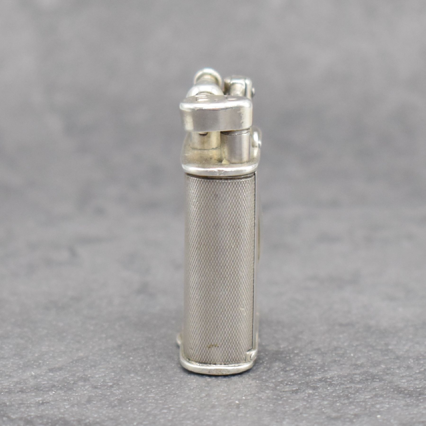 Detail a: Benzinfeuerzeug mit eingelassener Uhr in 900er Silber, Schweiz um 1930, rundum guill. Geh., Front mit Scharnier aufklappbar, Boden über verg. Werk ...