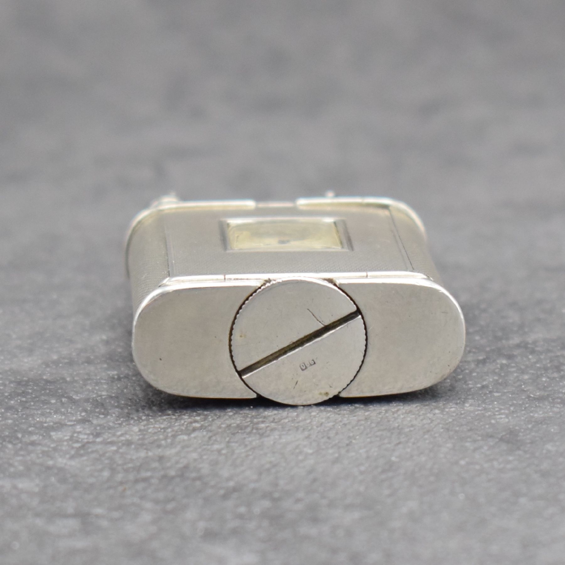 Detail d: Benzinfeuerzeug mit eingelassener Uhr in 900er Silber, Schweiz um 1930, rundum guill. Geh., Front mit Scharnier aufklappbar, Boden über verg. Werk ...