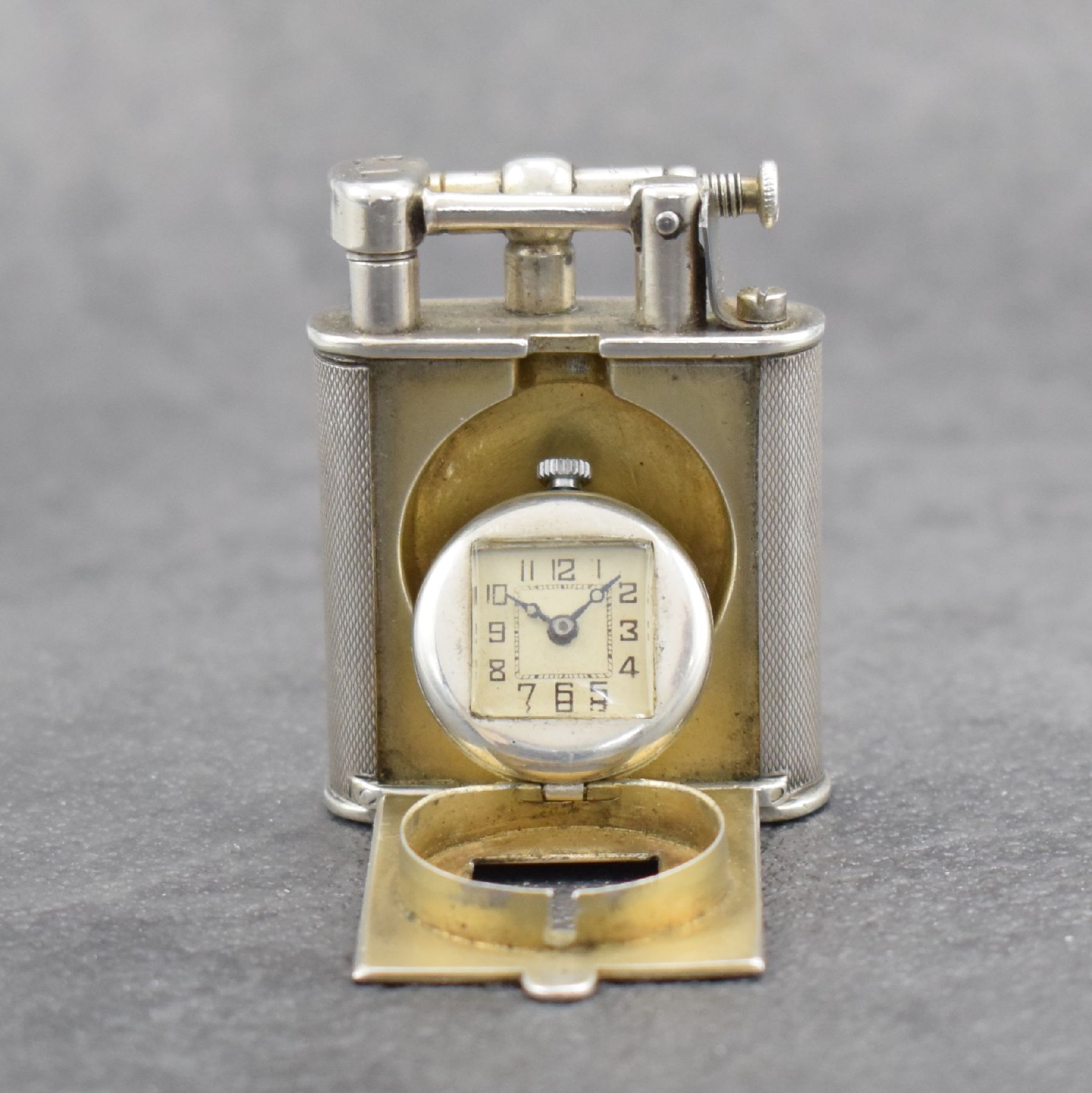 Detail f: Benzinfeuerzeug mit eingelassener Uhr in 900er Silber, Schweiz um 1930, rundum guill. Geh., Front mit Scharnier aufklappbar, Boden über verg. Werk ...