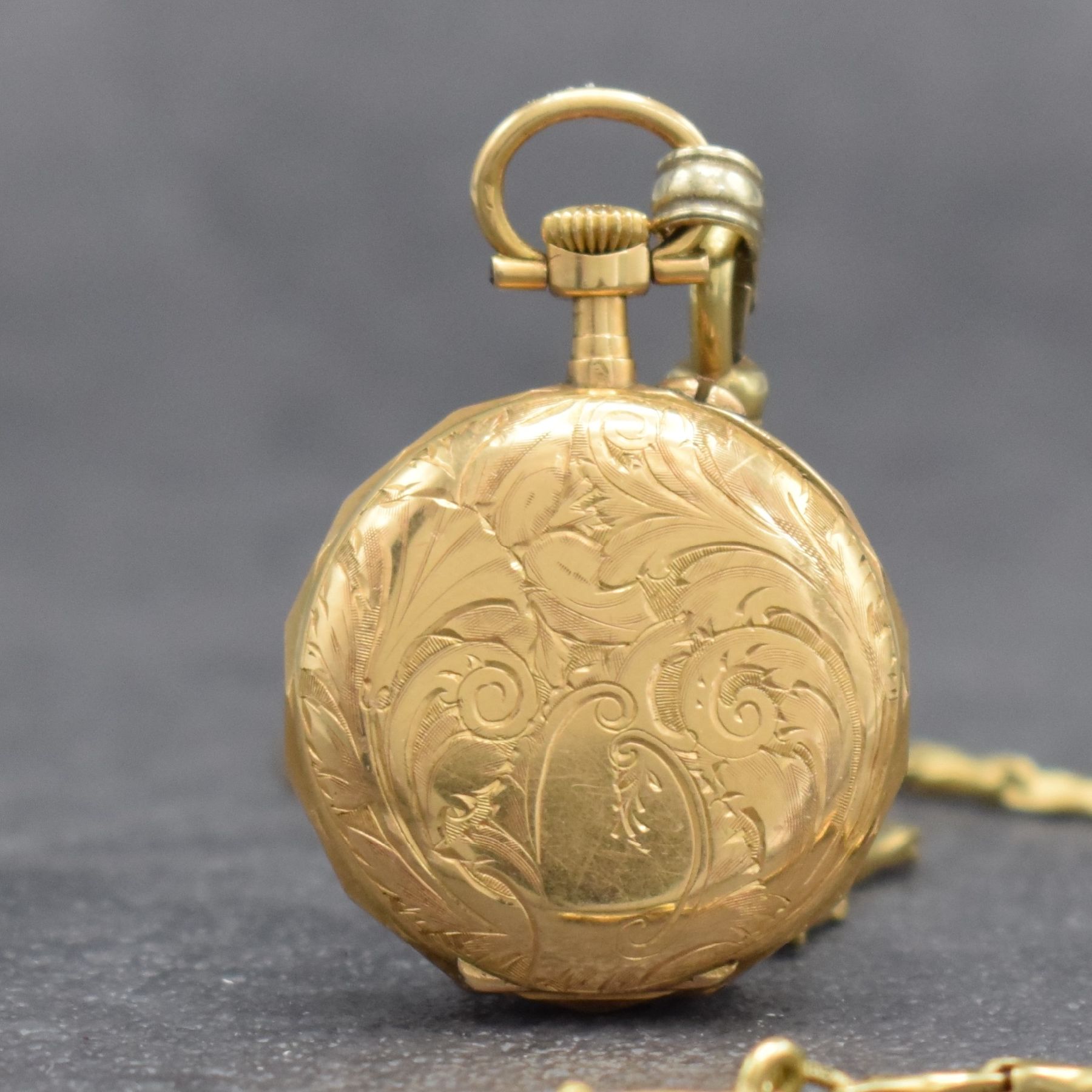 Detail c: Kleine Damentaschenuhr in GG 750/000 an GG 585/000 Kette, Schweiz um 1900, aufw. grav. Geh., Goldcuv., Emailzifferbl. m. röm. Std. & arab. ...