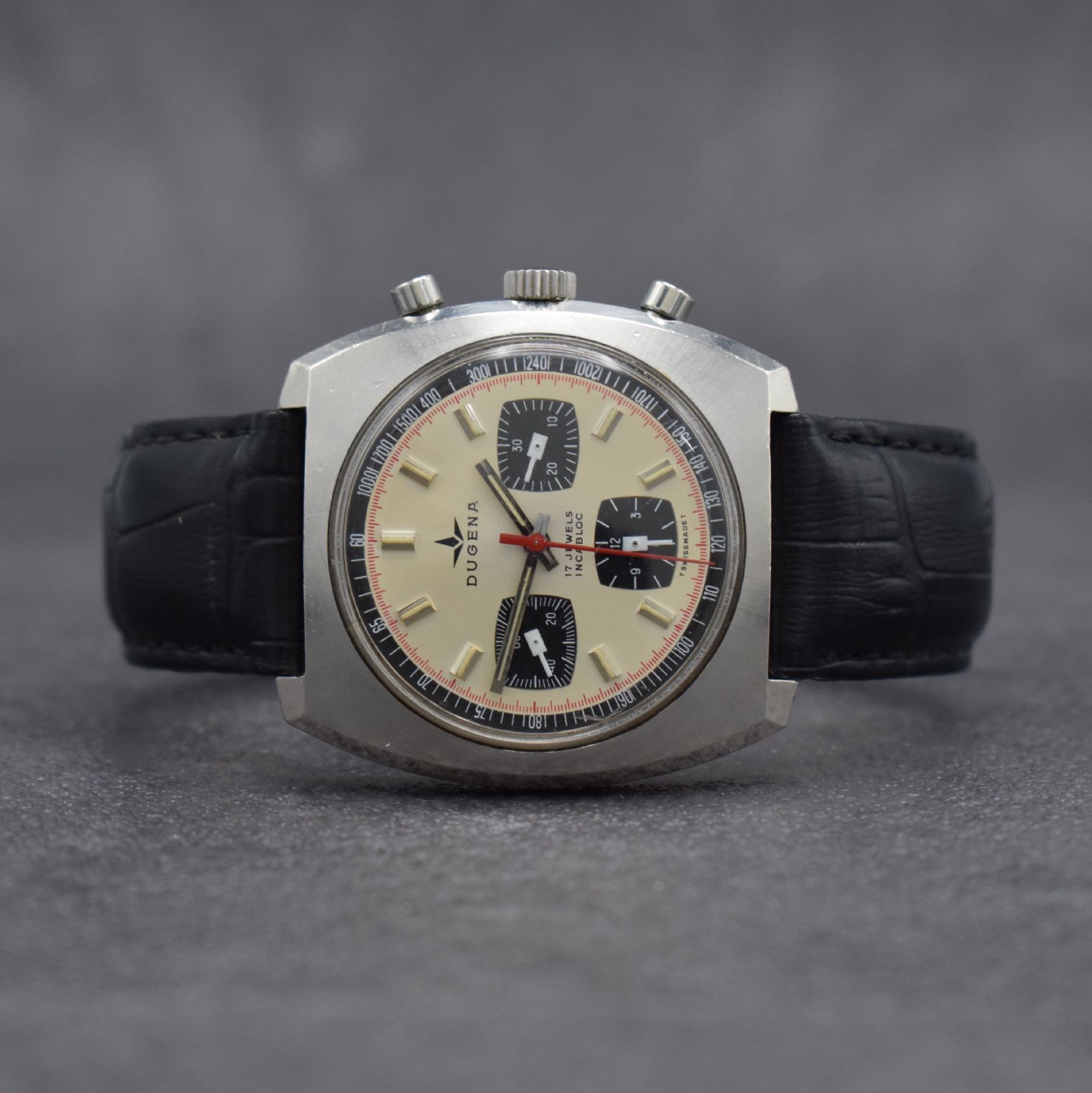 DUGENA Herrenarmbanduhr mit Chronograph, Schweiz um 1970, Handaufzug, massives Edelstahlgeh. m. geschr. Boden, silb. Zifferbl. m. aufges. Std.-Ind., ...
