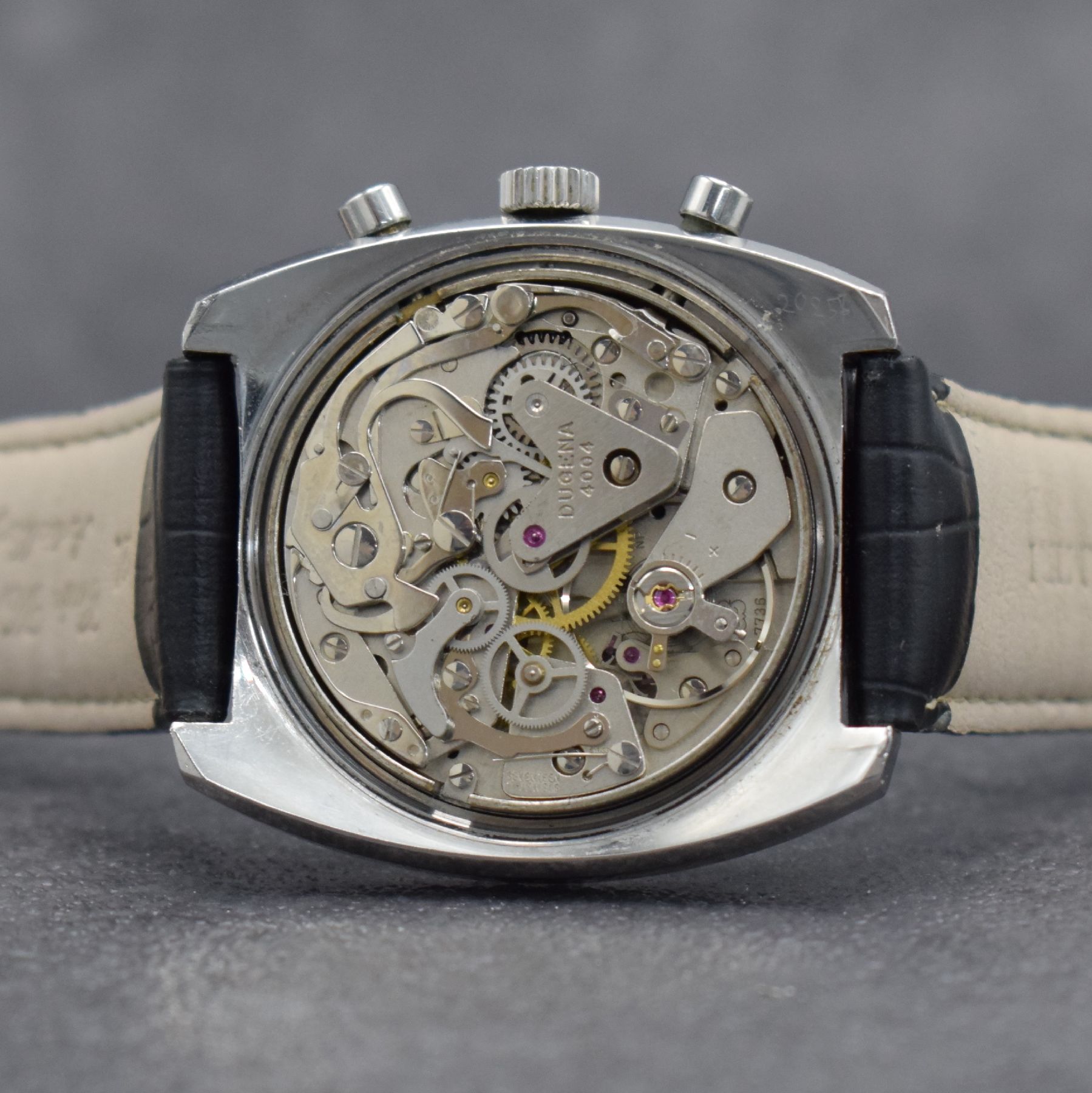 Detail f: DUGENA Herrenarmbanduhr mit Chronograph, Schweiz um 1970, Handaufzug, massives Edelstahlgeh. m. geschr. Boden, silb. Zifferbl. m. aufges. Std.-Ind., ...