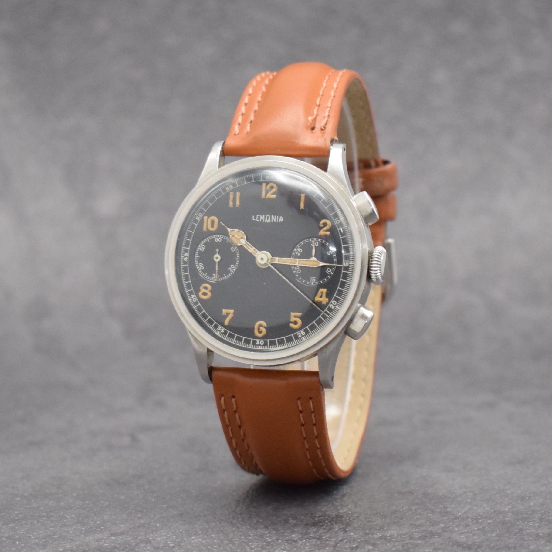 Detail e: LEMANIA Schaltradchronograph, Handaufzug, Schweiz 1940er Jahre, Edelstahlgeh., Boden & Glasrand aufgedr., schwarzes Zifferbl. m. fetten, arab. ...