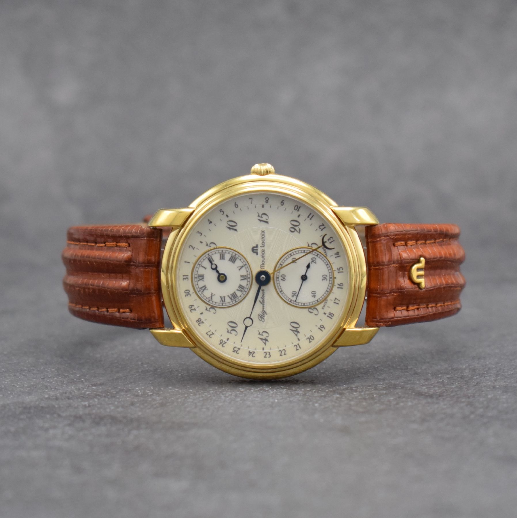 MAURICE LACROIX Regulateur vergoldete Herrenarmbanduhr, Schweiz um 1990, Handaufzug, beids. vergl. Geh., Boden & Glasrand aufgedr., orig. Lederband ...
