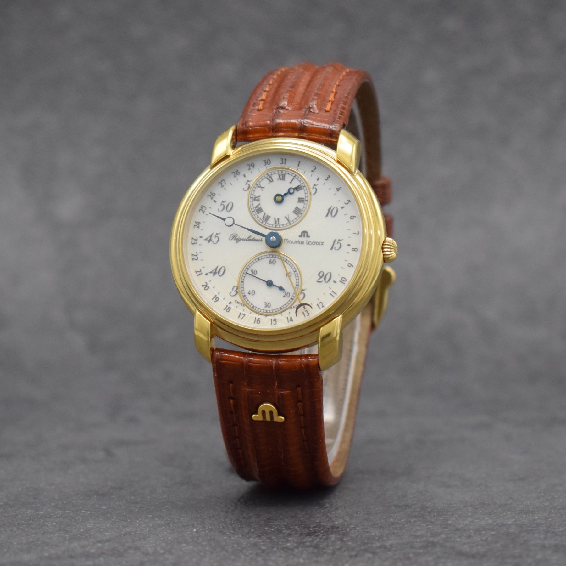 Detail b: MAURICE LACROIX Regulateur vergoldete Herrenarmbanduhr, Schweiz um 1990, Handaufzug, beids. vergl. Geh., Boden & Glasrand aufgedr., orig. Lederband ...