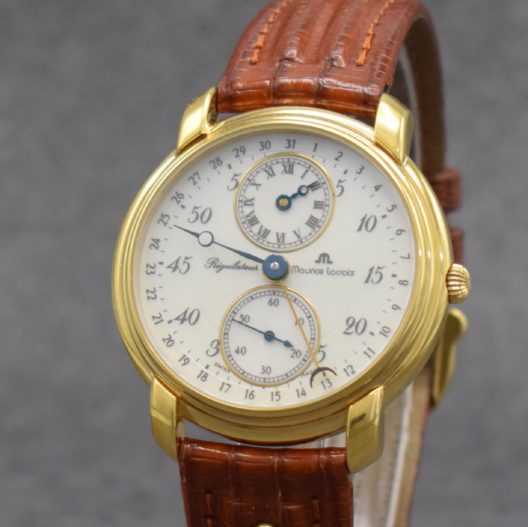 Detail c: MAURICE LACROIX Regulateur vergoldete Herrenarmbanduhr, Schweiz um 1990, Handaufzug, beids. vergl. Geh., Boden & Glasrand aufgedr., orig. Lederband ...