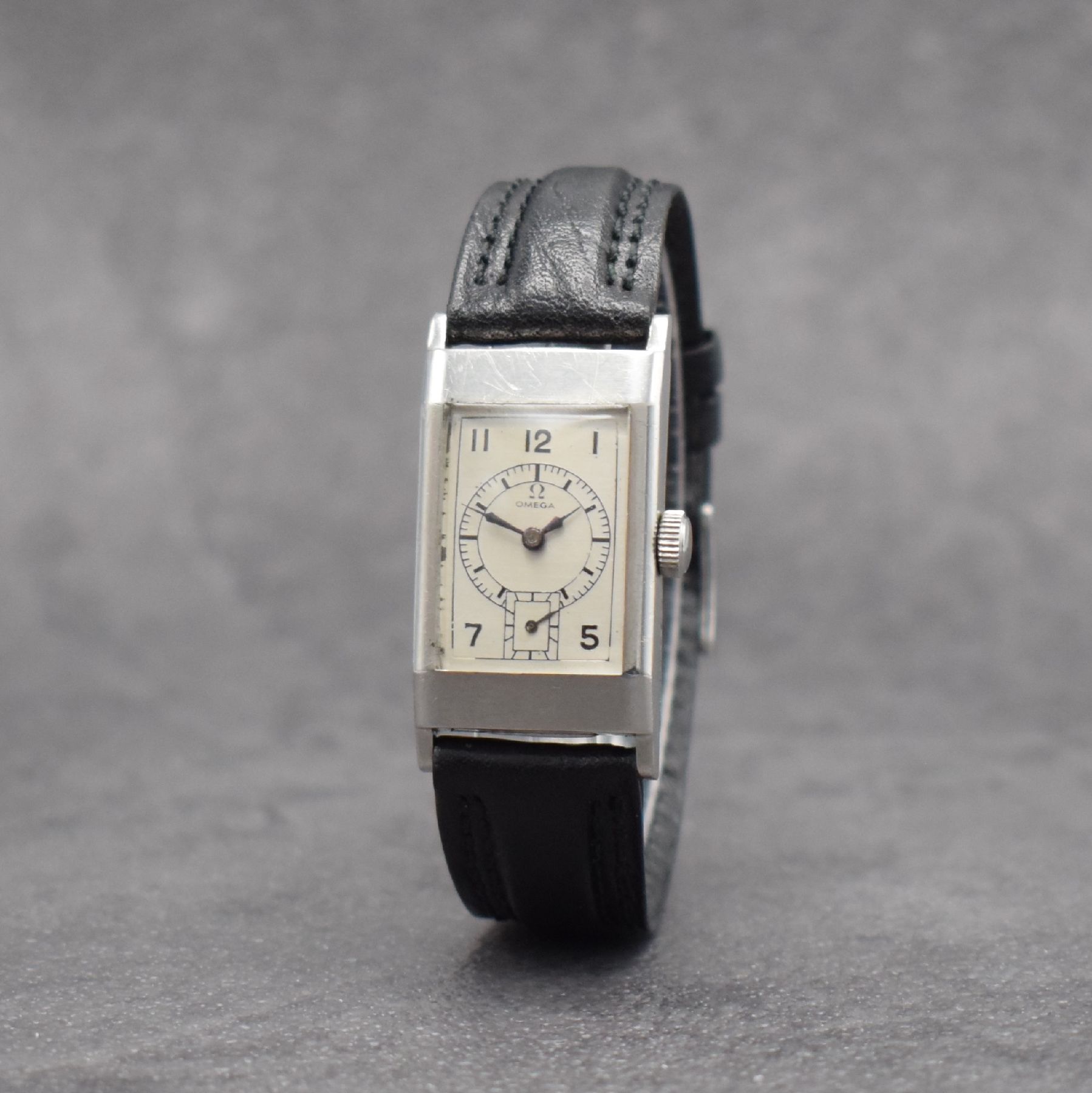 Detail b: OMEGA rechteckige Armbanduhr Kaliber T17, Schweiz um 1937, Handaufzug, leicht gewölbtes Edelstahlgehäuse, Boden aufgedr., silb. Zifferbl. ...