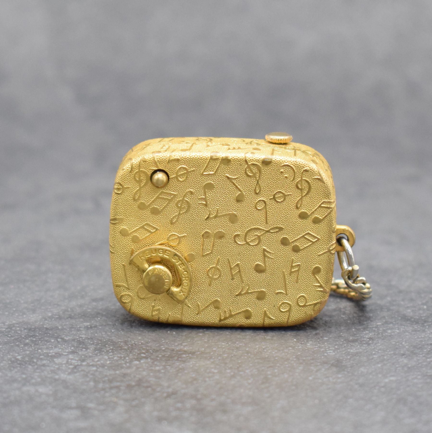Detail b: REUGE Miniatur-Spieluhr mit integrierter Uhr an Kette, Schweiz um 1960, klassische Melodie, verg. Gehäuse beids. guill. & mit Notenschlüsseln ...
