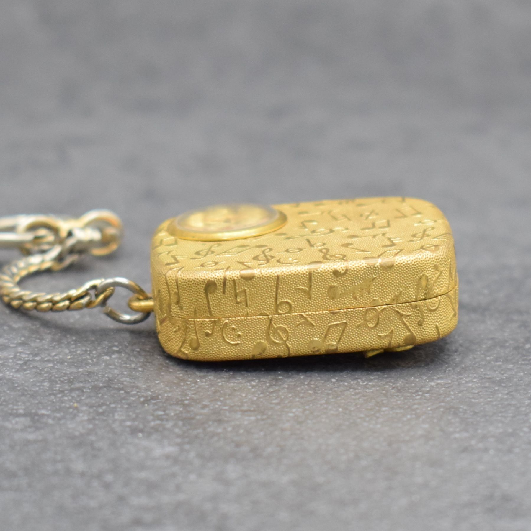 Detail d: REUGE Miniatur-Spieluhr mit integrierter Uhr an Kette, Schweiz um 1960, klassische Melodie, verg. Gehäuse beids. guill. & mit Notenschlüsseln ...