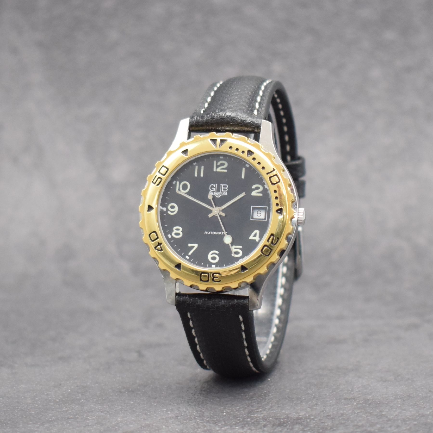 Detail b: GUB Herrenarmbanduhr, Schweiz/Deutschland um 1992, Automatik, gedr. Stahlgeh., Lünette m. 60er Teilung eins. rast. drehb., schwarzes Zifferbl. m. ...