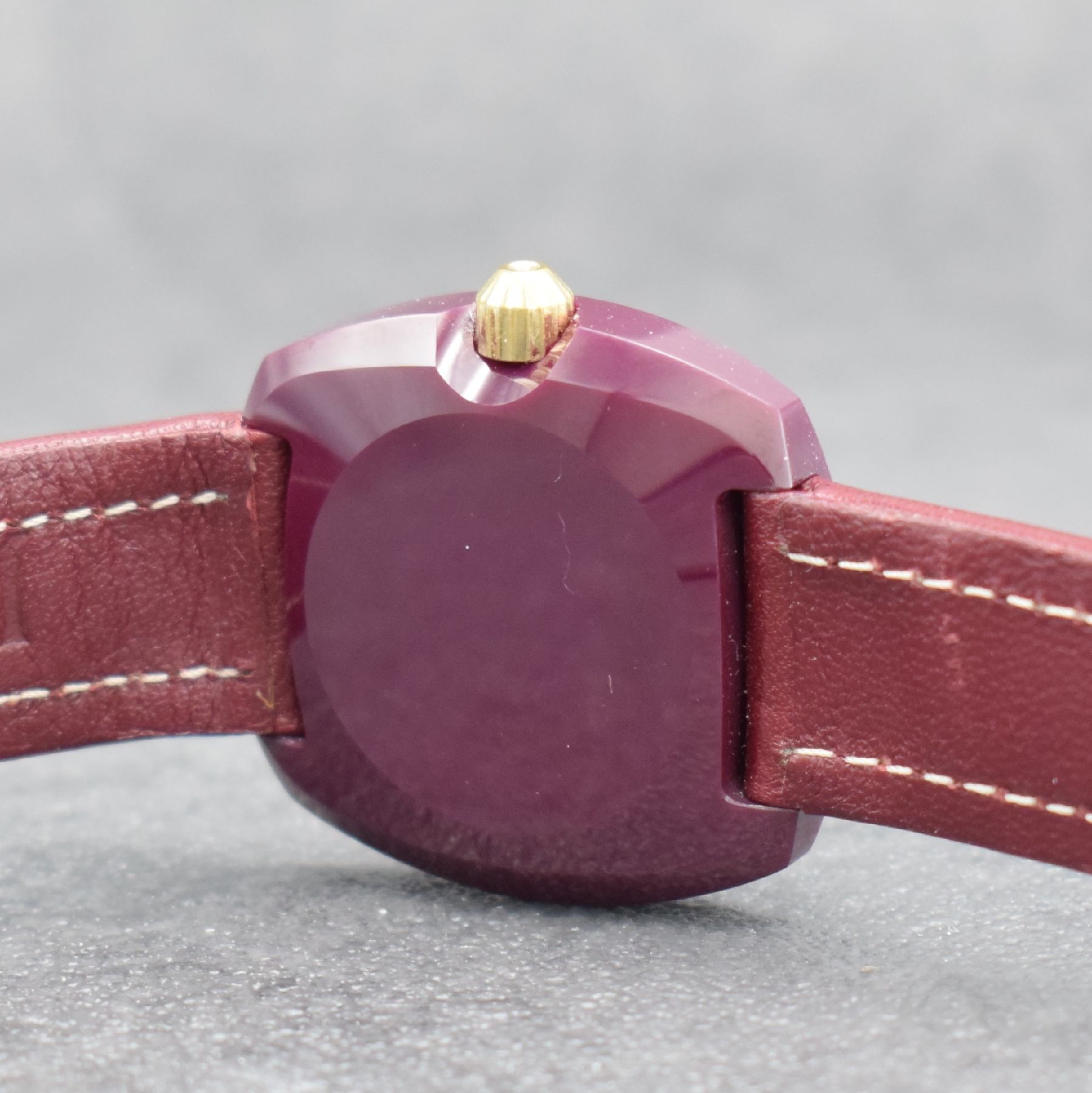 Detail d: VACUUM Armbanduhr im Rubin-Gehäuse, Schweiz um 1980, quarz, Monocoque-Geh., facettiertes Saphirglas m. 2 gold. Haltern rücks. verschr., Rubin-rotes ...