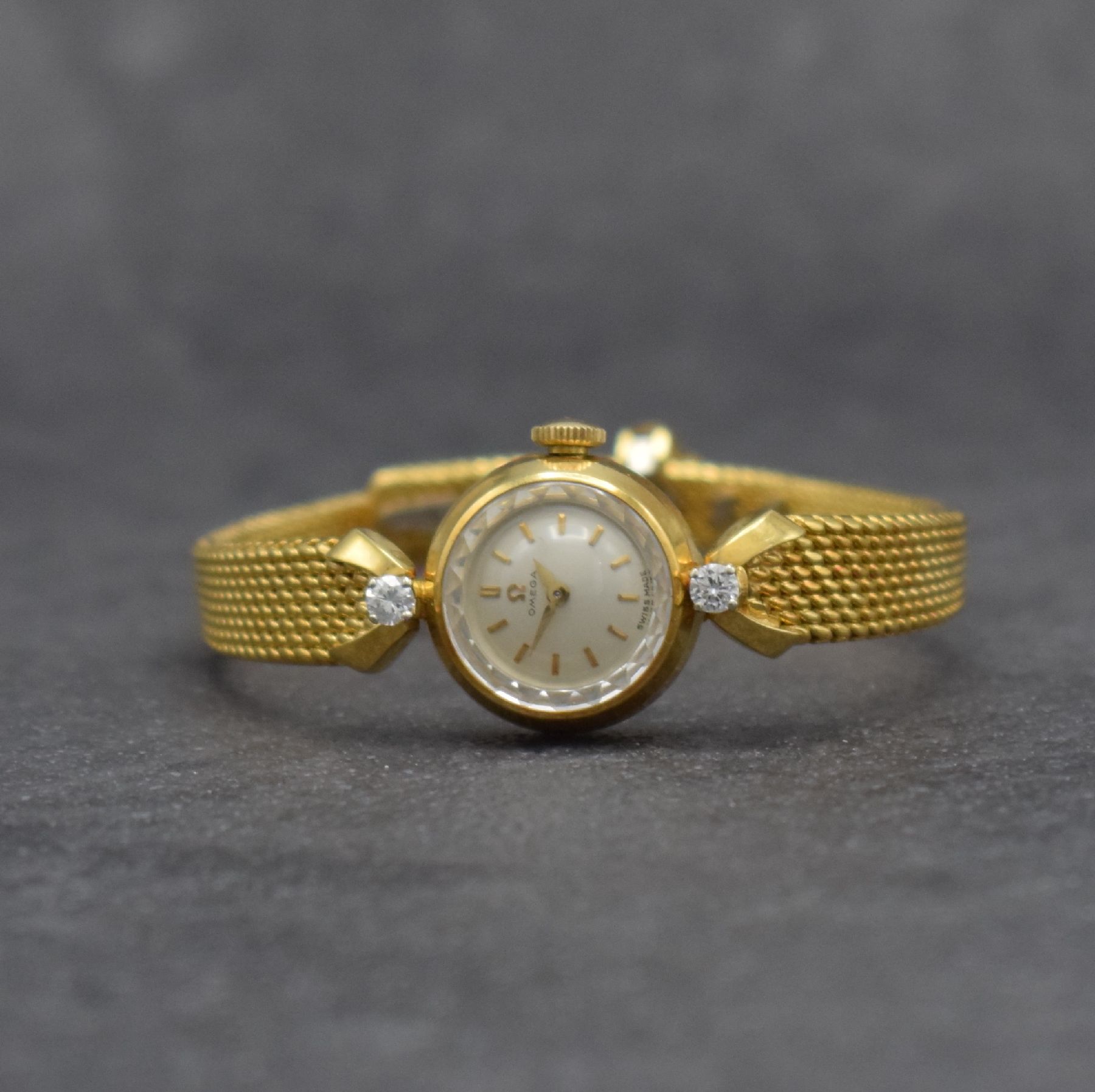 OMEGA Damenarmbanduhr in GG 750/000, Handaufzug, Schweiz um 1960, Ref. 7049, 2- teil. Geh., Boden aufgedr., Band zum Geh. m. 2 Diamanten bes., silb. ...
