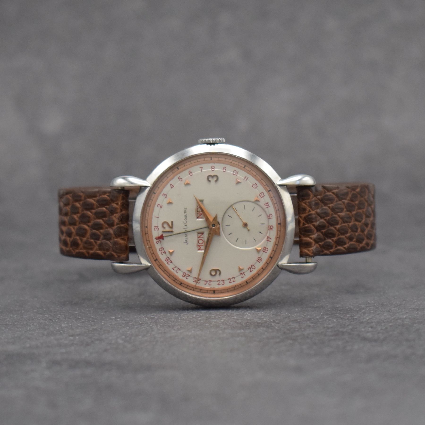 Jaeger-LeCoultre Herrenuhr mit Vollkalender in Stahl, Schweiz um 1945, Handaufzug, gedr. Geh. m. Tropfen-förm. Anstößen, silb./rose- farb. ...