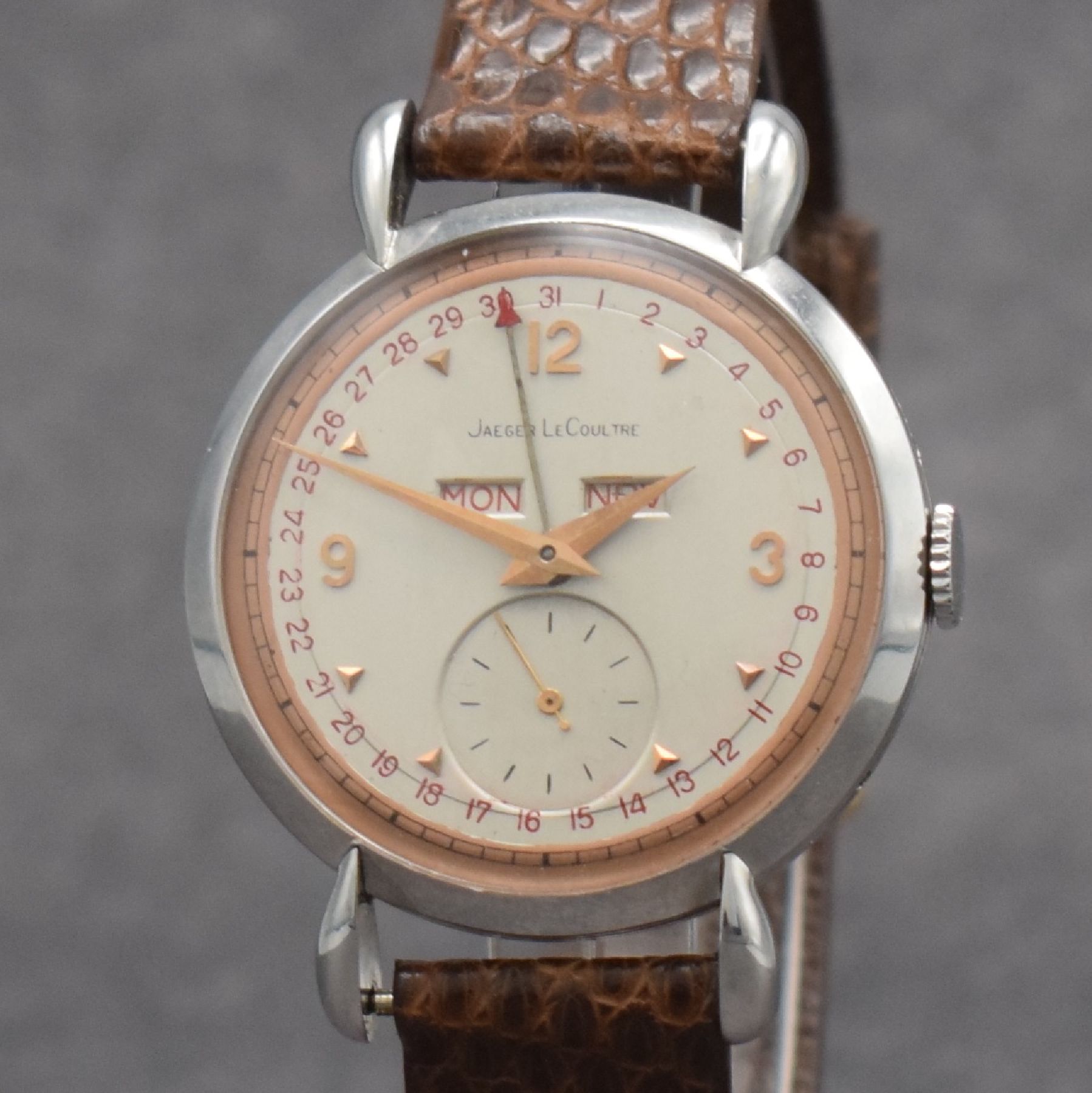 Detail c: Jaeger-LeCoultre Herrenuhr mit Vollkalender in Stahl, Schweiz um 1945, Handaufzug, gedr. Geh. m. Tropfen-förm. Anstößen, silb./rose- farb. ...