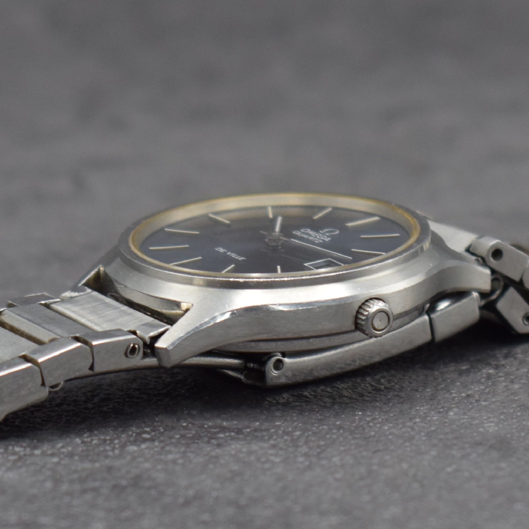 Detail d: OMEGA De Ville Herrenarmbanduhr in Stahl, Schweiz um 1978, quarz, 2-teil. Geh., Boden aufgedr., Stahlband später, graues Zifferbl. m. aufges. ...