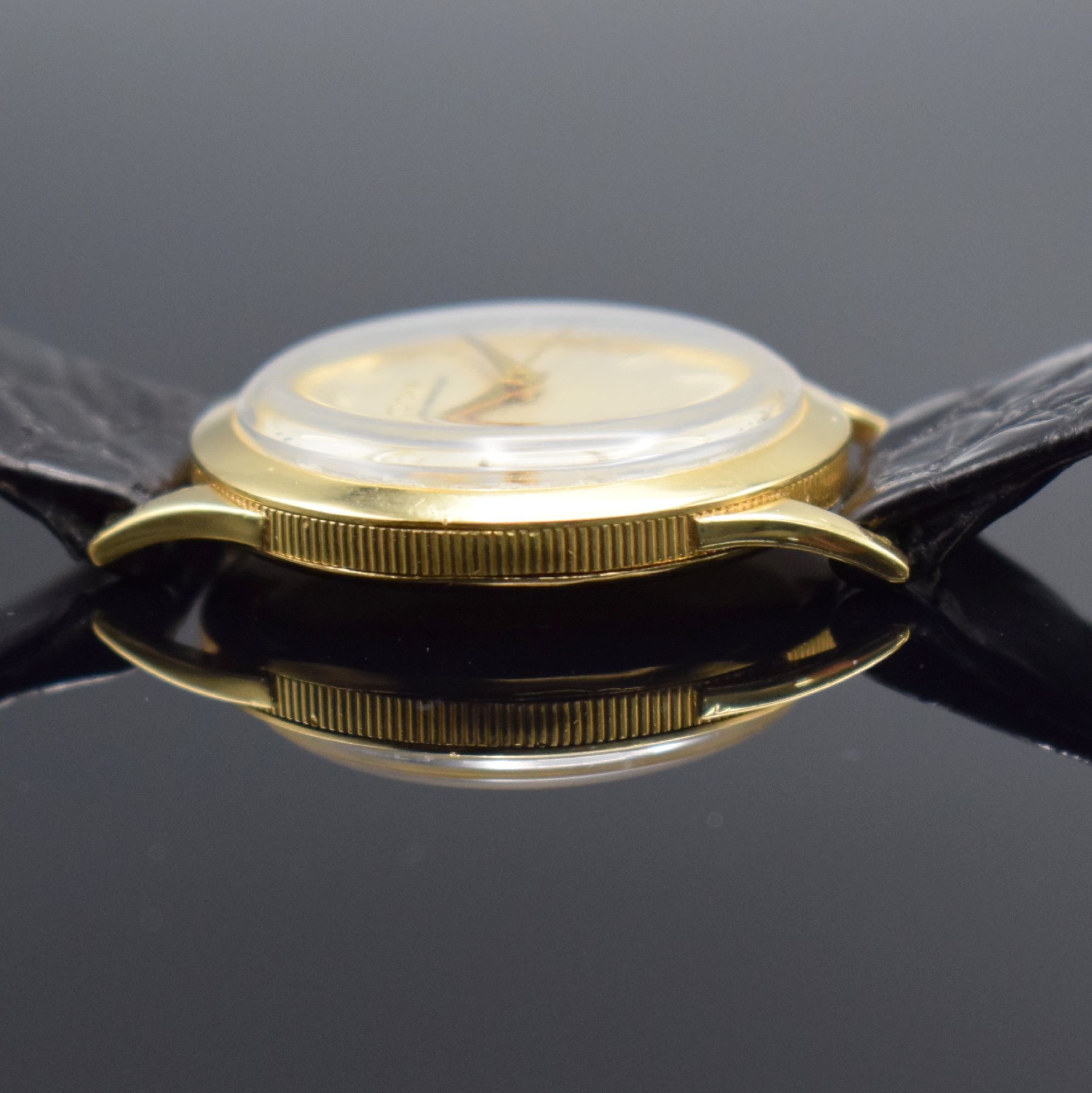 Detail e: DOXA Herrenarmbanduhr in GG 750/000, Schweiz um 1960, Handaufzug, 3-teil. Geh. m. Münzranddell., Boden & Glasrand aufgedr., silb. Zifferbl. m. gold. ...