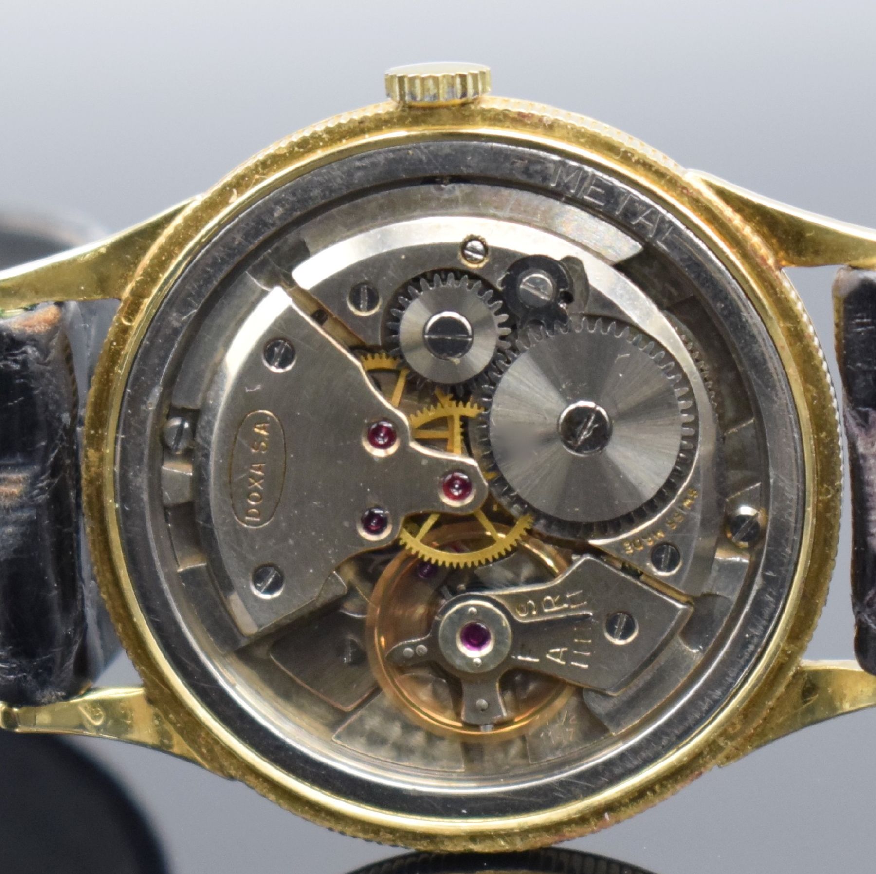 Detail g: DOXA Herrenarmbanduhr in GG 750/000, Schweiz um 1960, Handaufzug, 3-teil. Geh. m. Münzranddell., Boden & Glasrand aufgedr., silb. Zifferbl. m. gold. ...