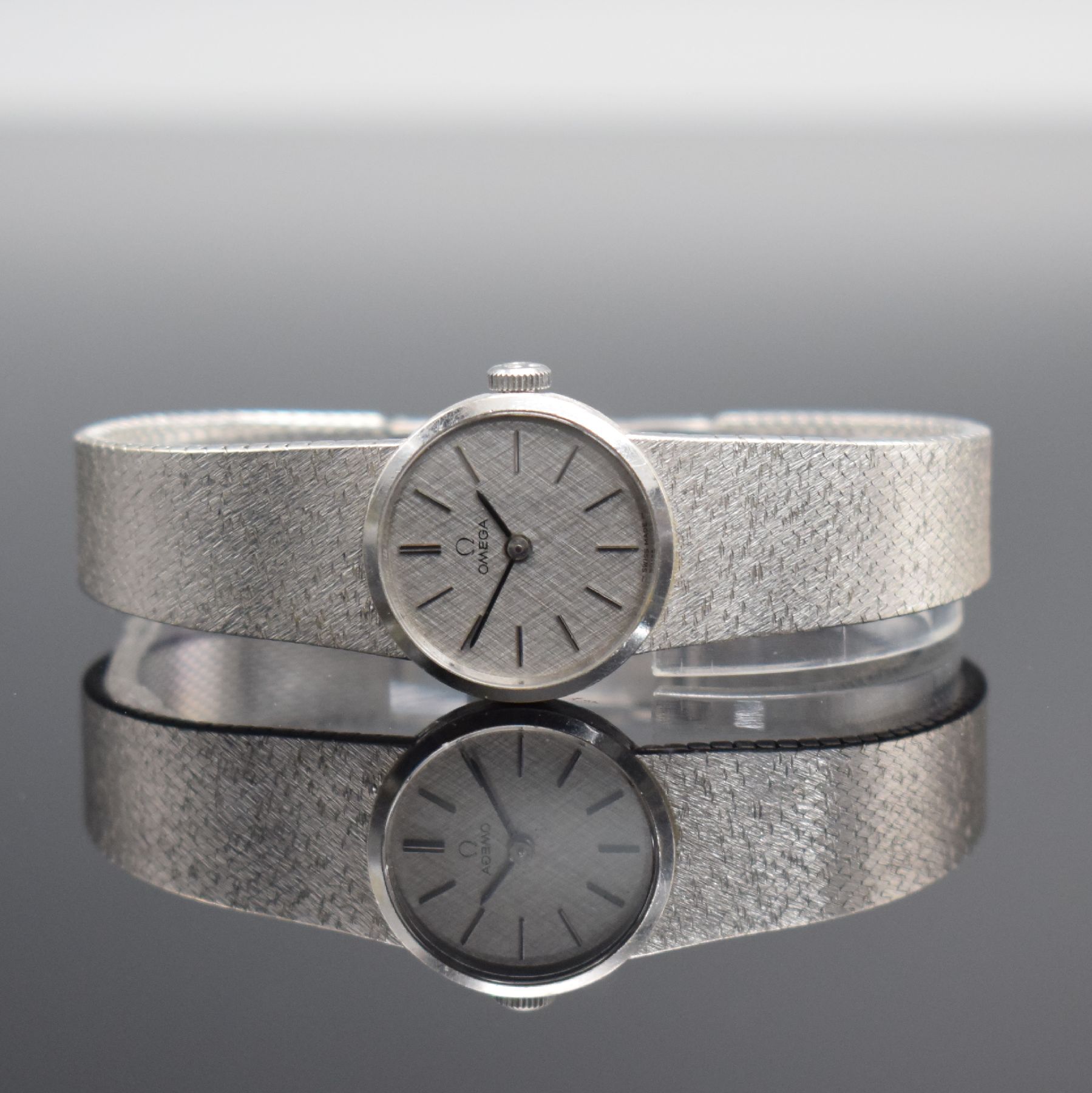 OMEGA Damenarmbanduhr in WG 585/000, Schweiz um 1973, Handaufzug, Boden aufgedr., orig. Milanaiseband in WG 585/000, silb. Strukturzifferbl. m. ...