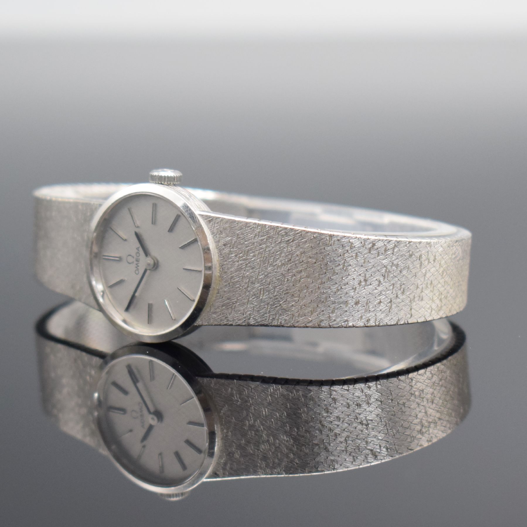 Detail d: OMEGA Damenarmbanduhr in WG 585/000, Schweiz um 1973, Handaufzug, Boden aufgedr., orig. Milanaiseband in WG 585/000, silb. Strukturzifferbl. m. ...