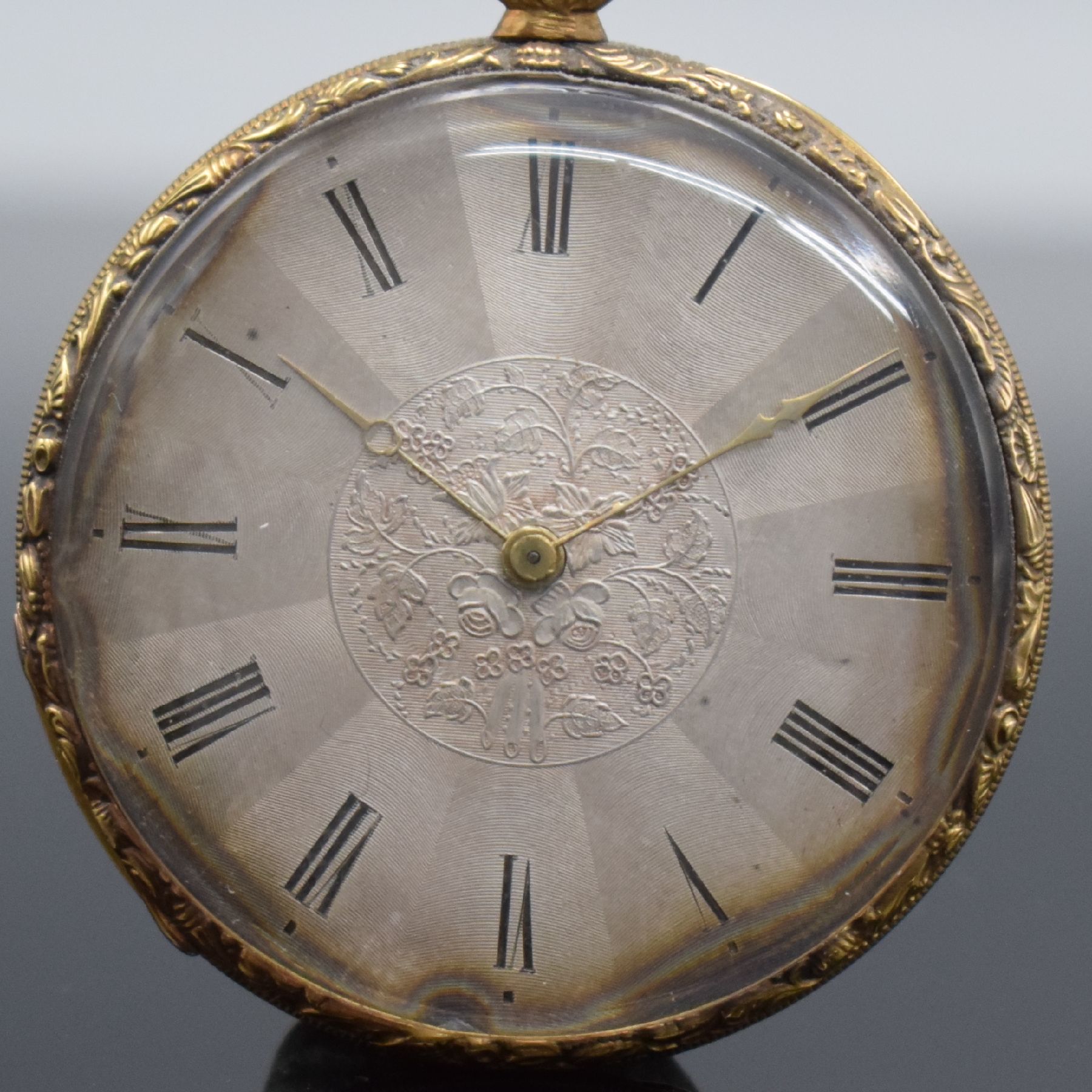 Detail a: Offene Taschenuhr in GG 750/000, Schweiz um 1850, Metallcuvette, floral grav. Ränder, guill. Rückseite, silb. Zifferbl. m. röm. Zahlen z. T. ...