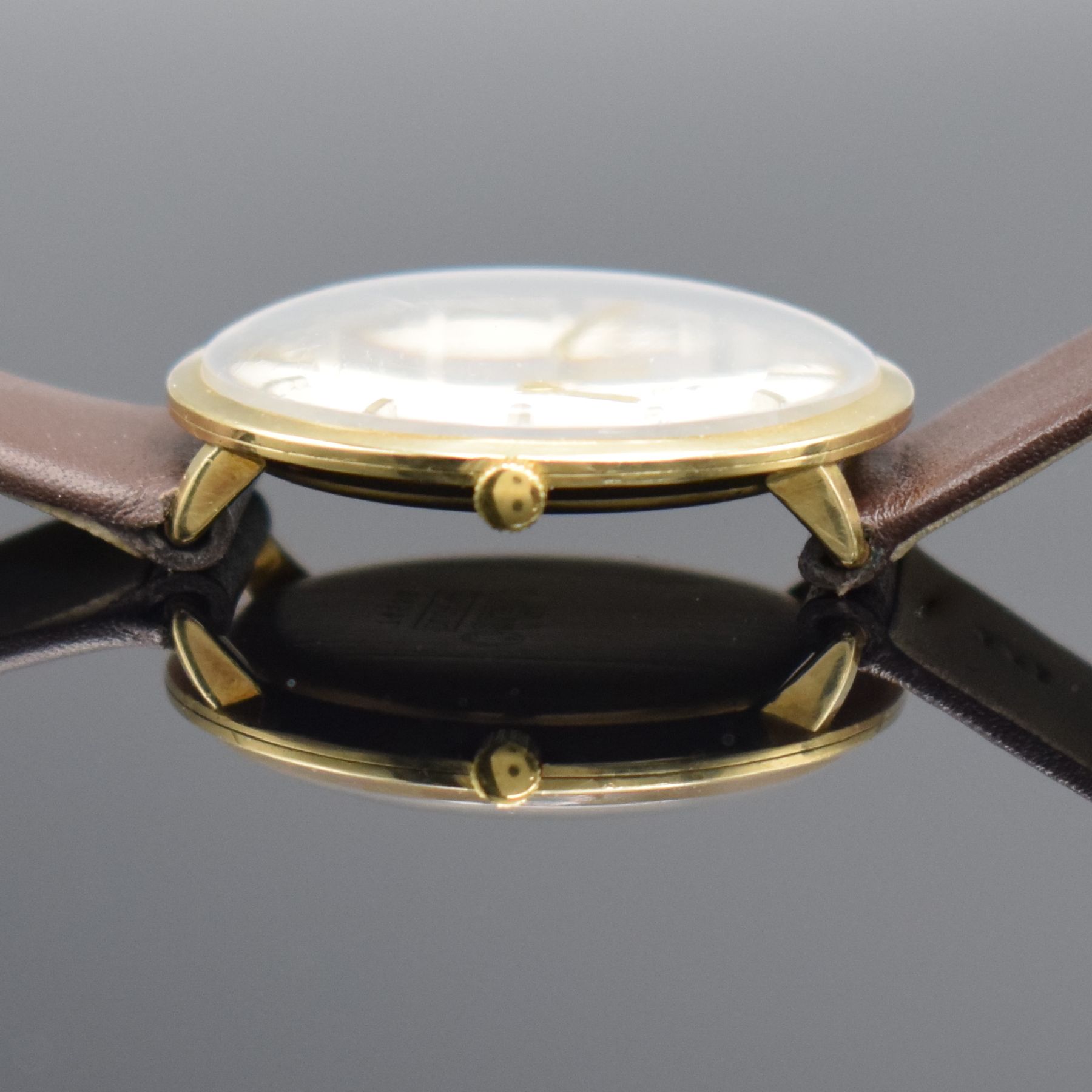 Detail d: DUGENA Armbanduhr in GG 585/000, Schweiz um 1960, Handaufzug, 3-teil. Geh., Boden & Glasrand aufgedr., silb. Zifferbl. m. aufges. Std.-Ind., gold. ...
