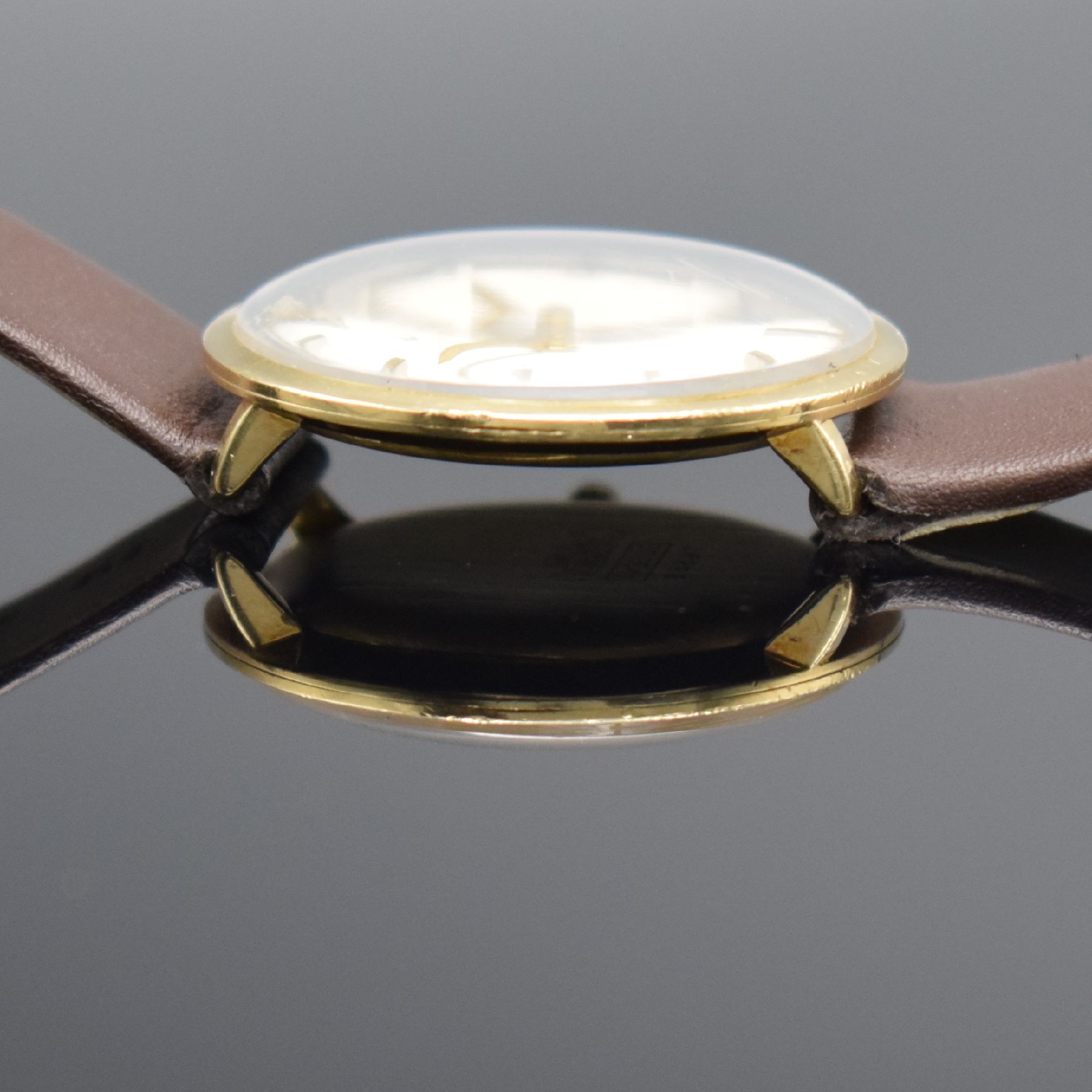 Detail e: DUGENA Armbanduhr in GG 585/000, Schweiz um 1960, Handaufzug, 3-teil. Geh., Boden & Glasrand aufgedr., silb. Zifferbl. m. aufges. Std.-Ind., gold. ...