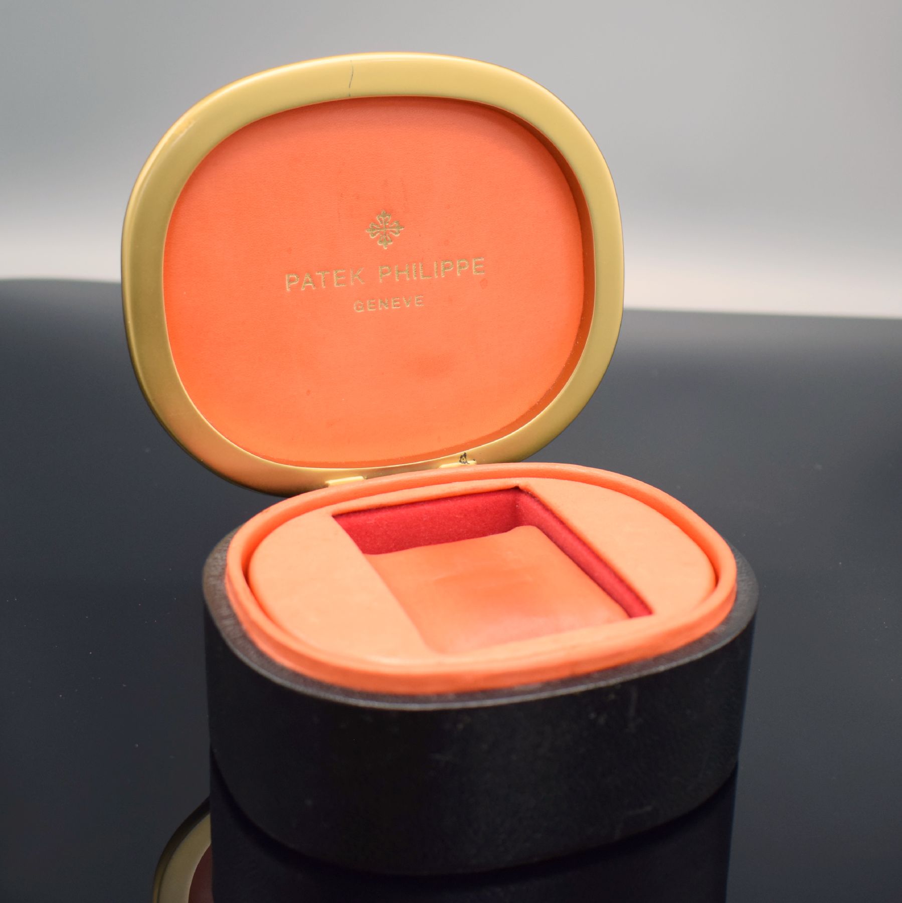 PATEK PHILIPPE Ellipse-förmige Uhrenbox in schwarzem Leder, 1970er Jahre, gold. Rand, innen rotes Leder, M. ca. 6 x 13 x 11 cm, voll nutzbar