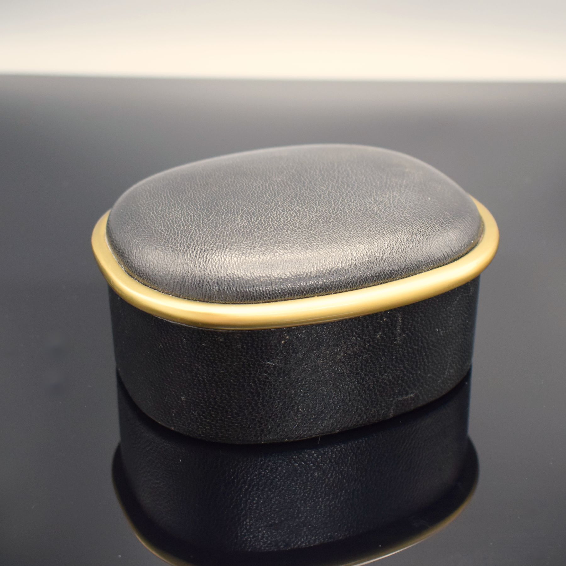 Detail c: PATEK PHILIPPE Ellipse-förmige Uhrenbox in schwarzem Leder, 1970er Jahre, gold. Rand, innen rotes Leder, M. ca. 6 x 13 x 11 cm, voll nutzbar