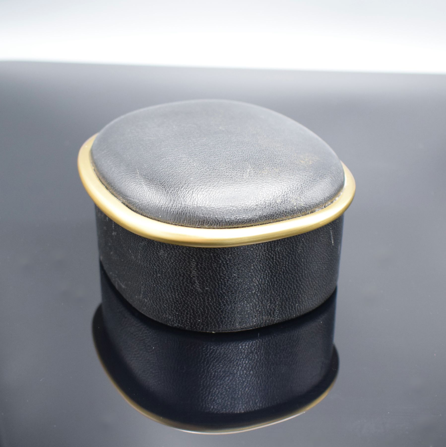Detail e: PATEK PHILIPPE Ellipse-förmige Uhrenbox in schwarzem Leder, 1970er Jahre, gold. Rand, innen rotes Leder, M. ca. 6 x 13 x 11 cm, voll nutzbar
