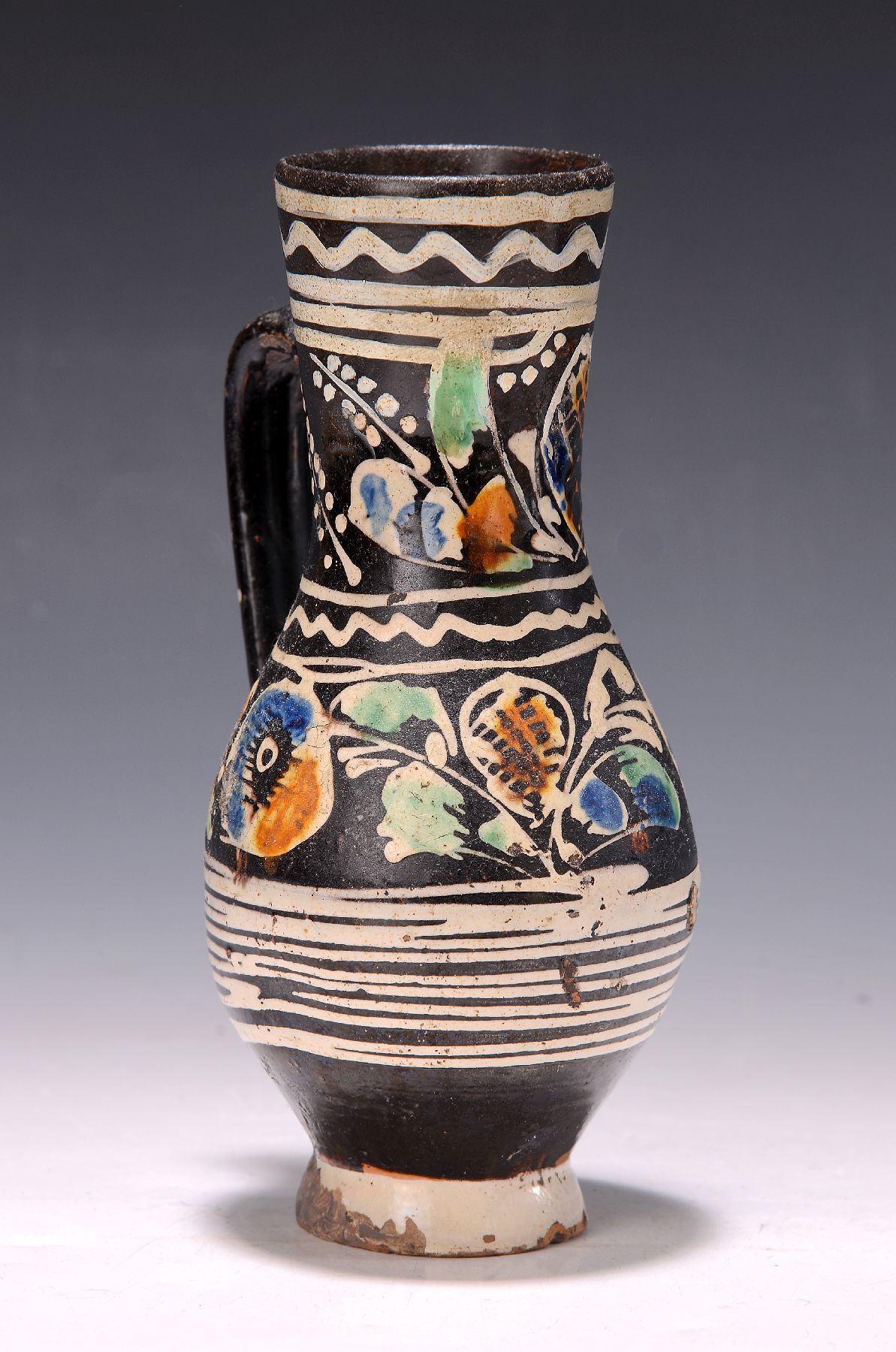 Krug, Ungarn, um 1820-40, Fayence, schwarzgrundig, bunt bemalt mit stil. Blumen, H. ca. 23cm, an der Wandung restauriert
