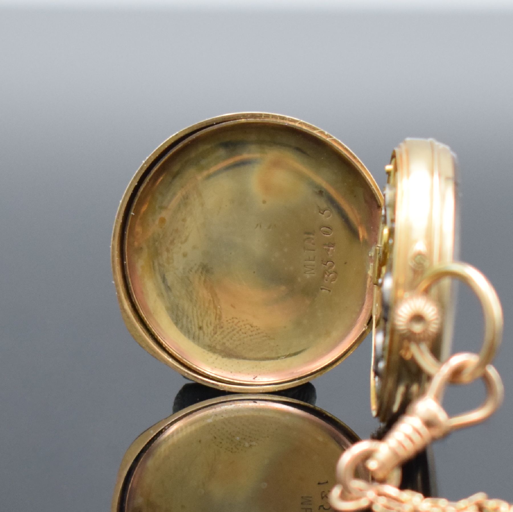 Detail e: Offene Damentaschenuhr in RG 585/000 mit Kettein RG 585/000, Schweiz um 1890, Kette später, Metallcuvette, floral grav. Rückseite, Emailzifferbl. ...