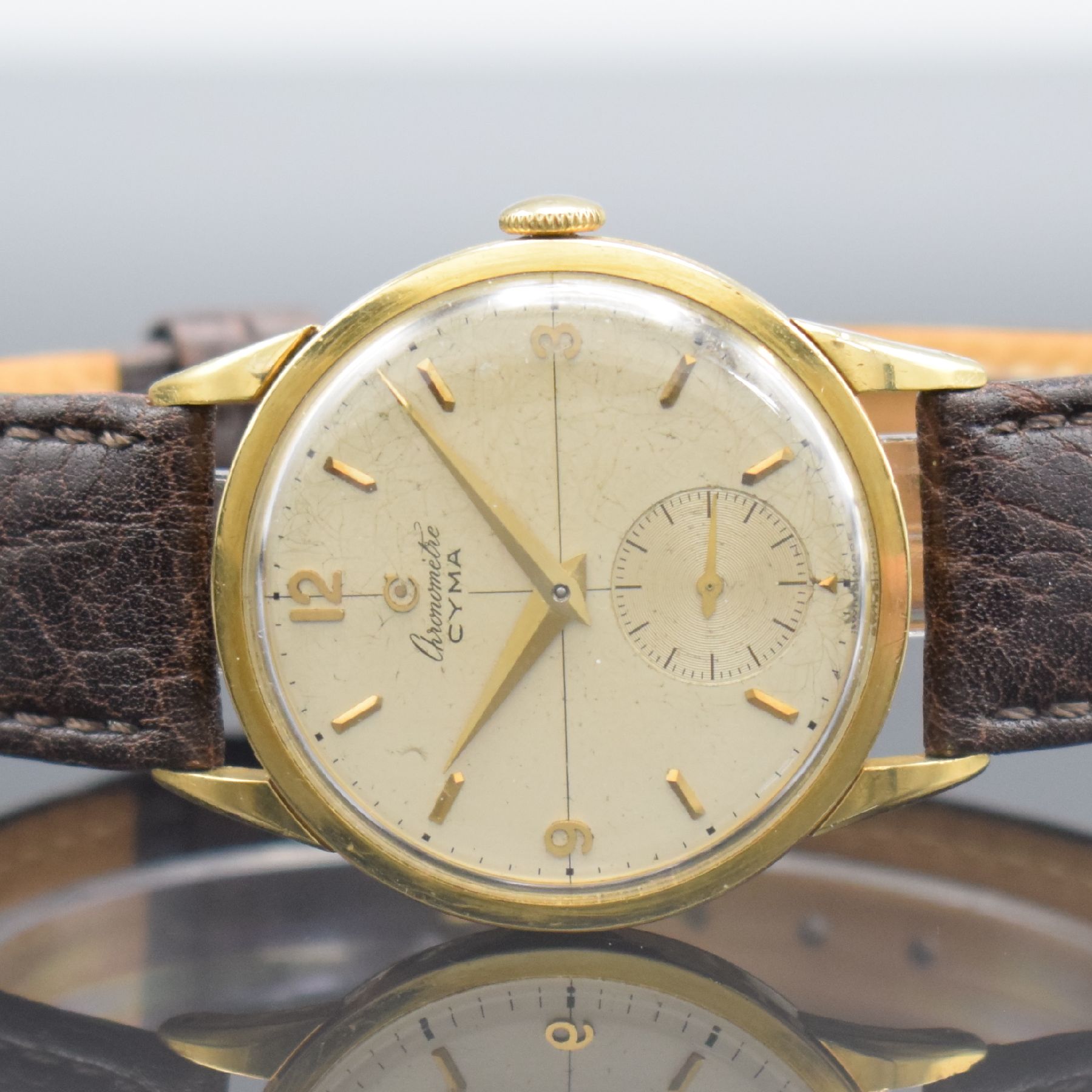 Detail a: CYMA Chronometer seltene Herrenarmbanduhr in GG 750/000, Schweiz um 1950, 3-tlg. Geh., Boden & Glasrand aufgedr., silb. Zifferbl. fl./pat., aufges. ...