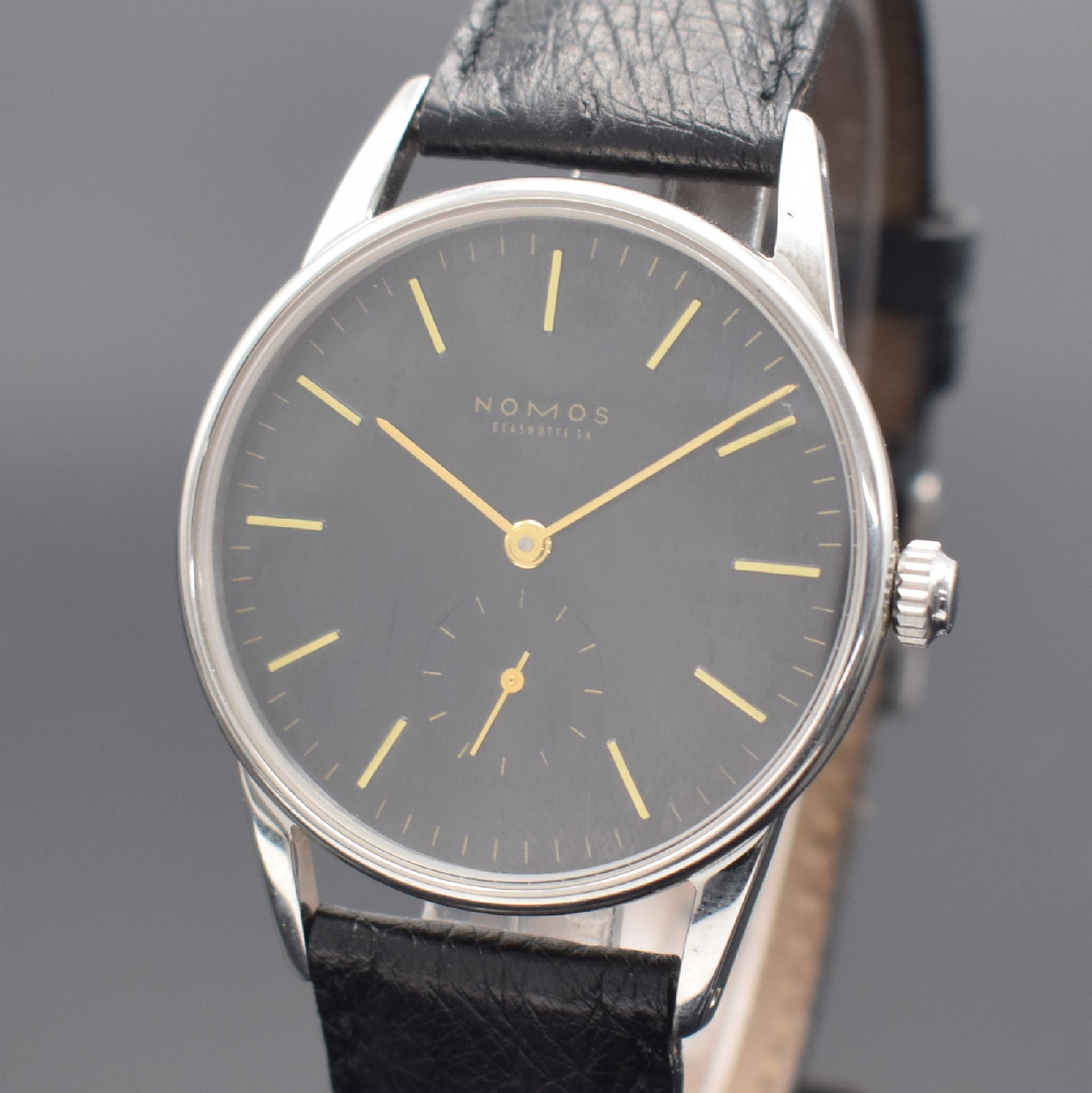 Detail a: NOMOS Herrenarmbanduhr Orion, Handaufzug, 3 -teil. Edelstahlgeh., Boden & Glasrand aufgedr., schwarzes Zifferbl. m. gold. Indizes, gold. Zeiger, Anz. ...