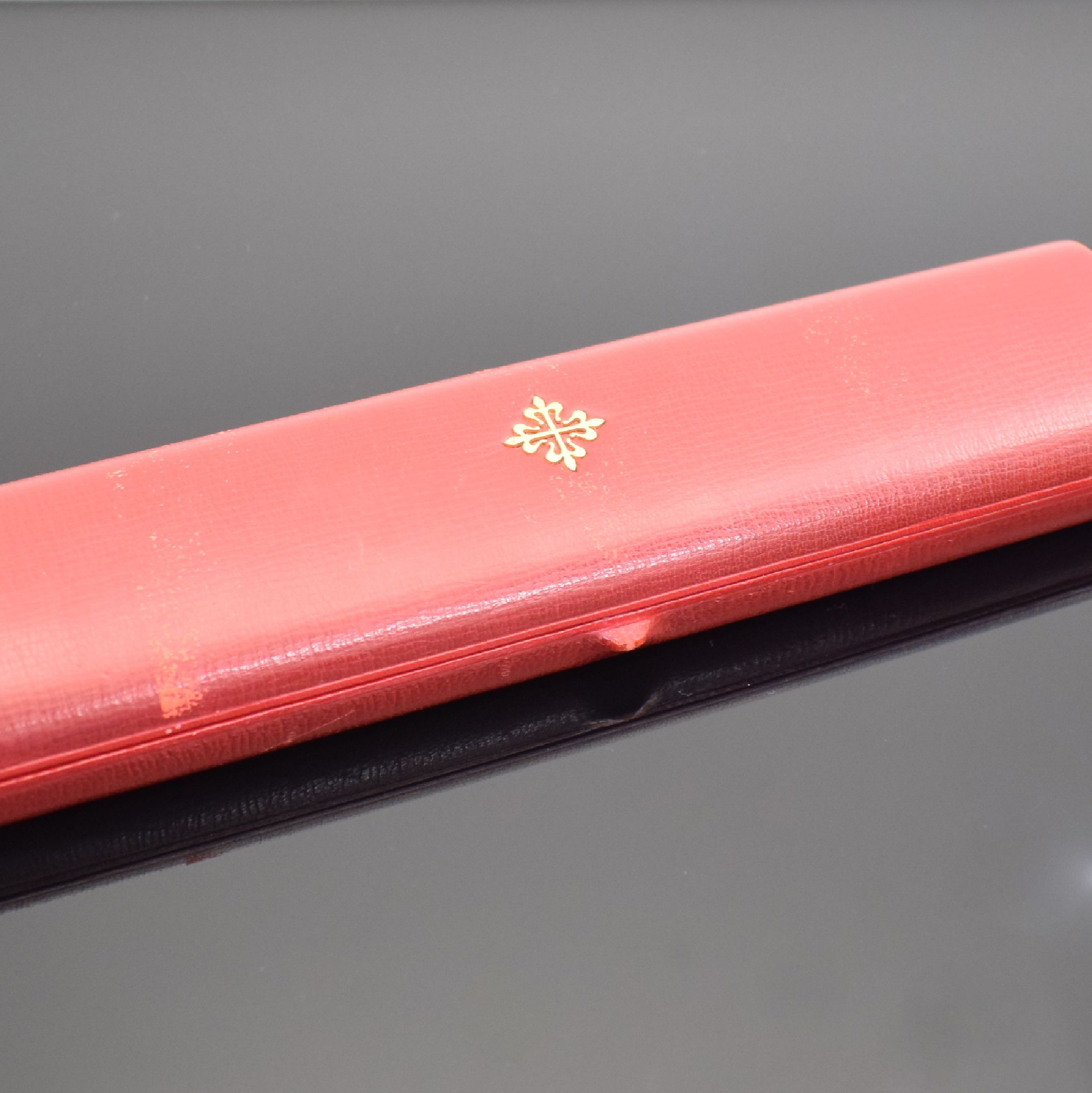Detail a: PATEK PHILIPPE hochwertiges, pultförmiges Armbanduhr-Etui, Schweiz um 1960, außen rot, Deckel mit zentral aufgel. Calatrava Kreuz, innen ...