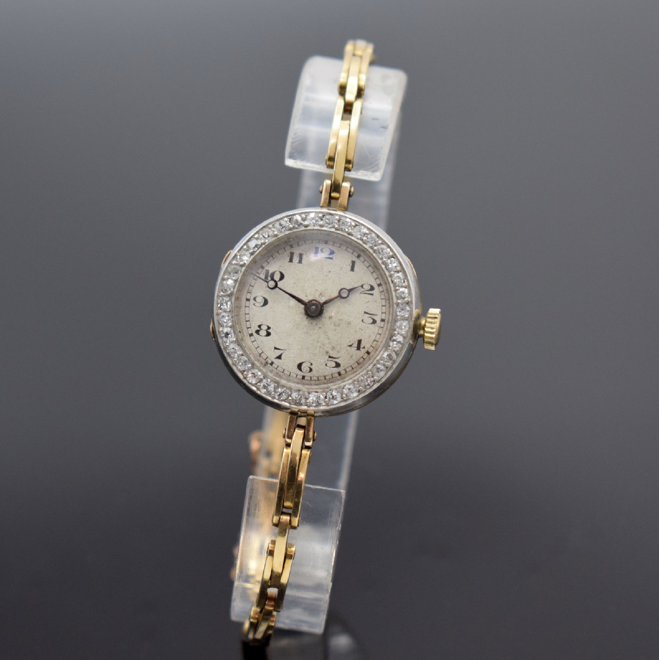 Frühe Damenarmbanduhr in GG 585/000, Schweiz um 1920, Handaufzug, 3-teil. Geh., Goldband m. Sicherheitskettchen, Lünette in WG 333/000 m. Diamanten ...