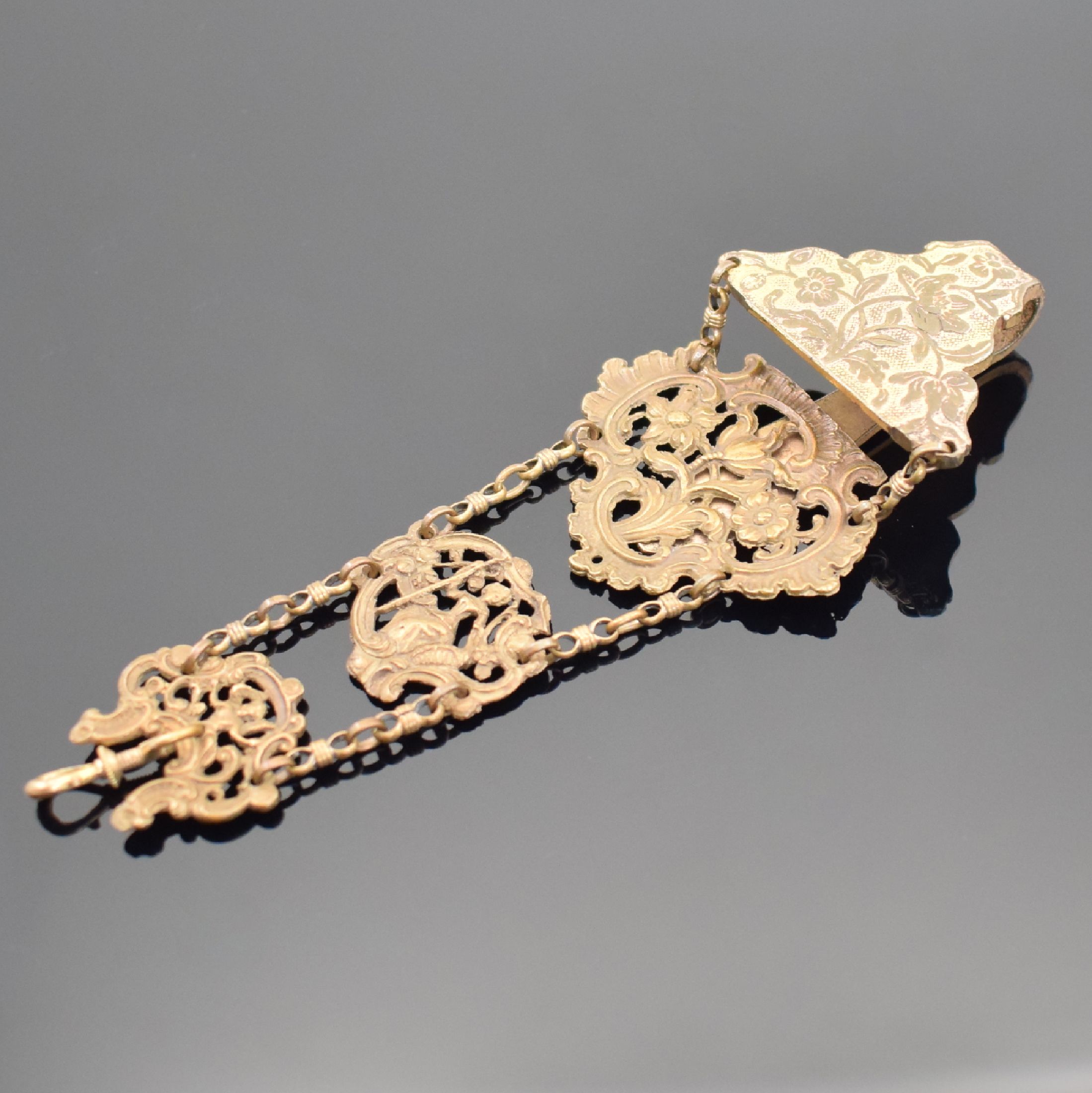 Detail a: 2 vergoldete Chatelaines, 19. Jhd., verschr. Karabiner, 1. 3-reihig, 2 durchbr. Elemente, 3-farb. vergold., 2. 3 durchbr. Elemente im Rococo-Stil, L. ...